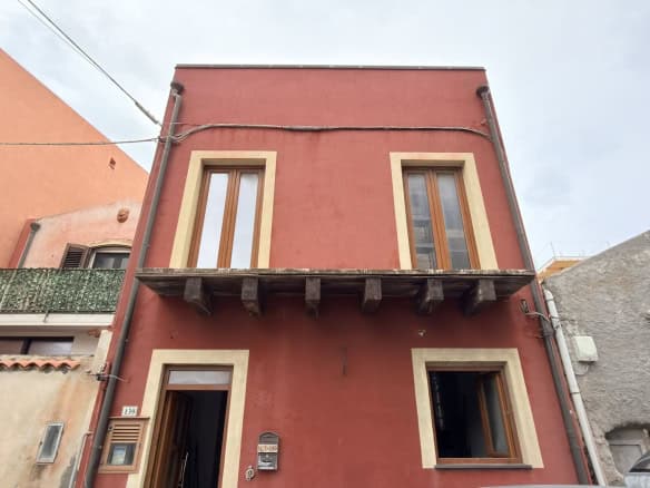 Ampio immobile residenziale in stile classico con facciata rossa e dettagli in beige, dotato di finestre grandi e balcone, situato in zona urbana tranquilla e ben collegata.