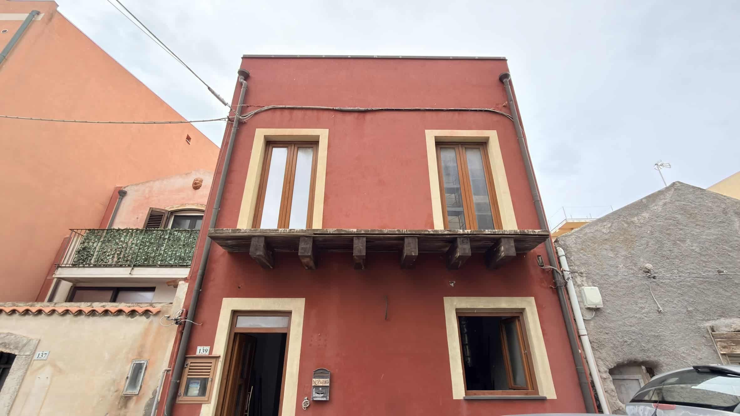 Ampio immobile residenziale in stile classico con facciata rossa e dettagli in beige, dotato di finestre grandi e balcone, situato in zona urbana tranquilla e ben collegata.
