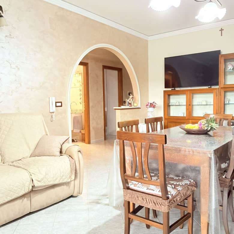 Soggiorno spazioso e luminoso con divano beige e tavolo da pranzo in legno, ideale per famiglie, in un appartamento in stile classico con arredi accoglienti e atmosfera calda.
