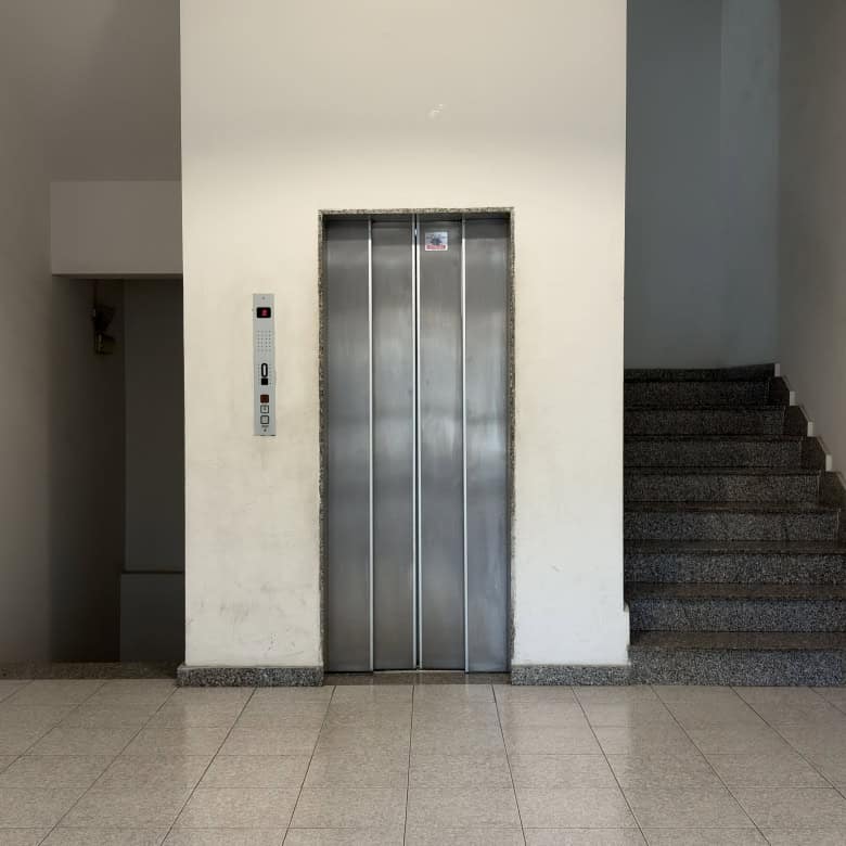 Ascensore condominiale in un edificio moderno, situato tra le scale, pronto per il trasporto di persone e bagagli.