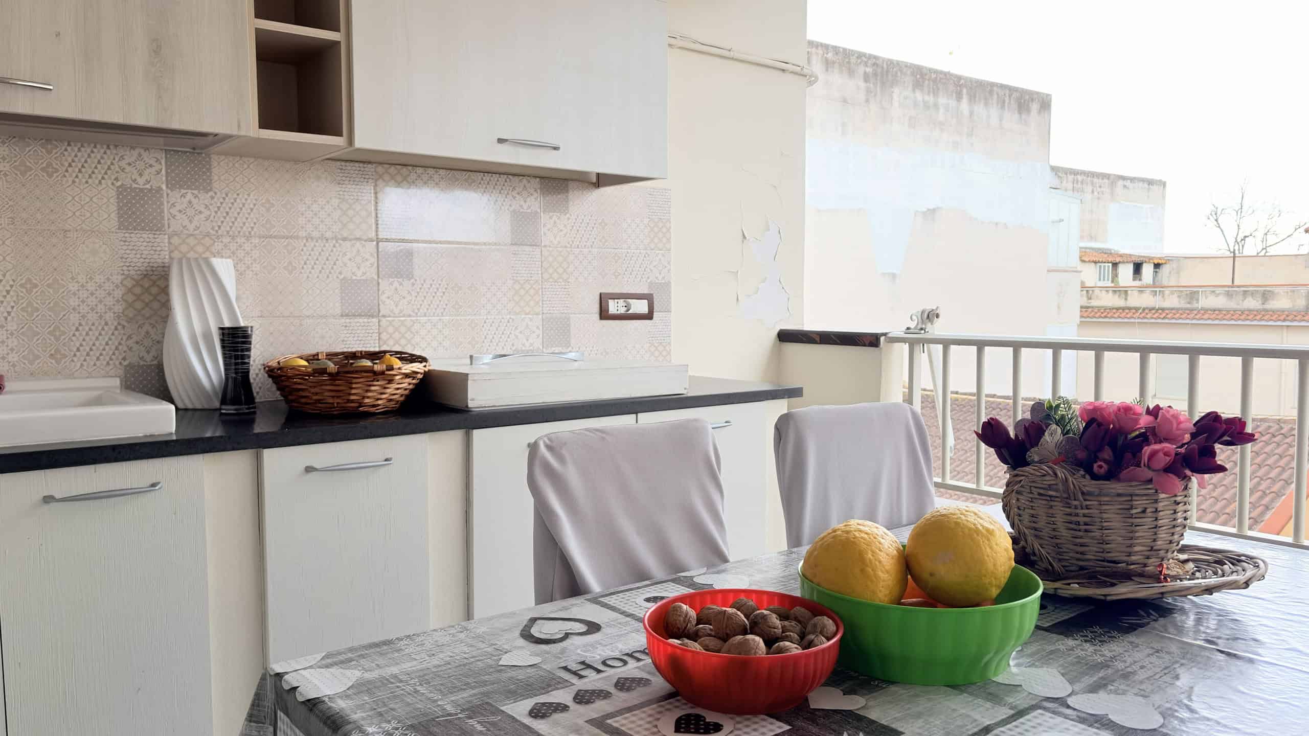 Cucina moderna con tavolo da pranzo, frutta fresca e decorazioni eleganti, ambiente luminoso e accogliente.