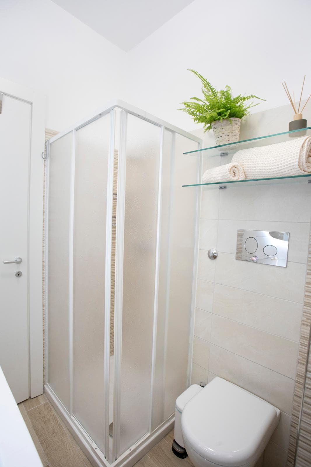 Lavabo e doccia in un bagno moderno con pareti chiare, accessori di design e piante verdi, ideale per ambienti di comfort e stile.