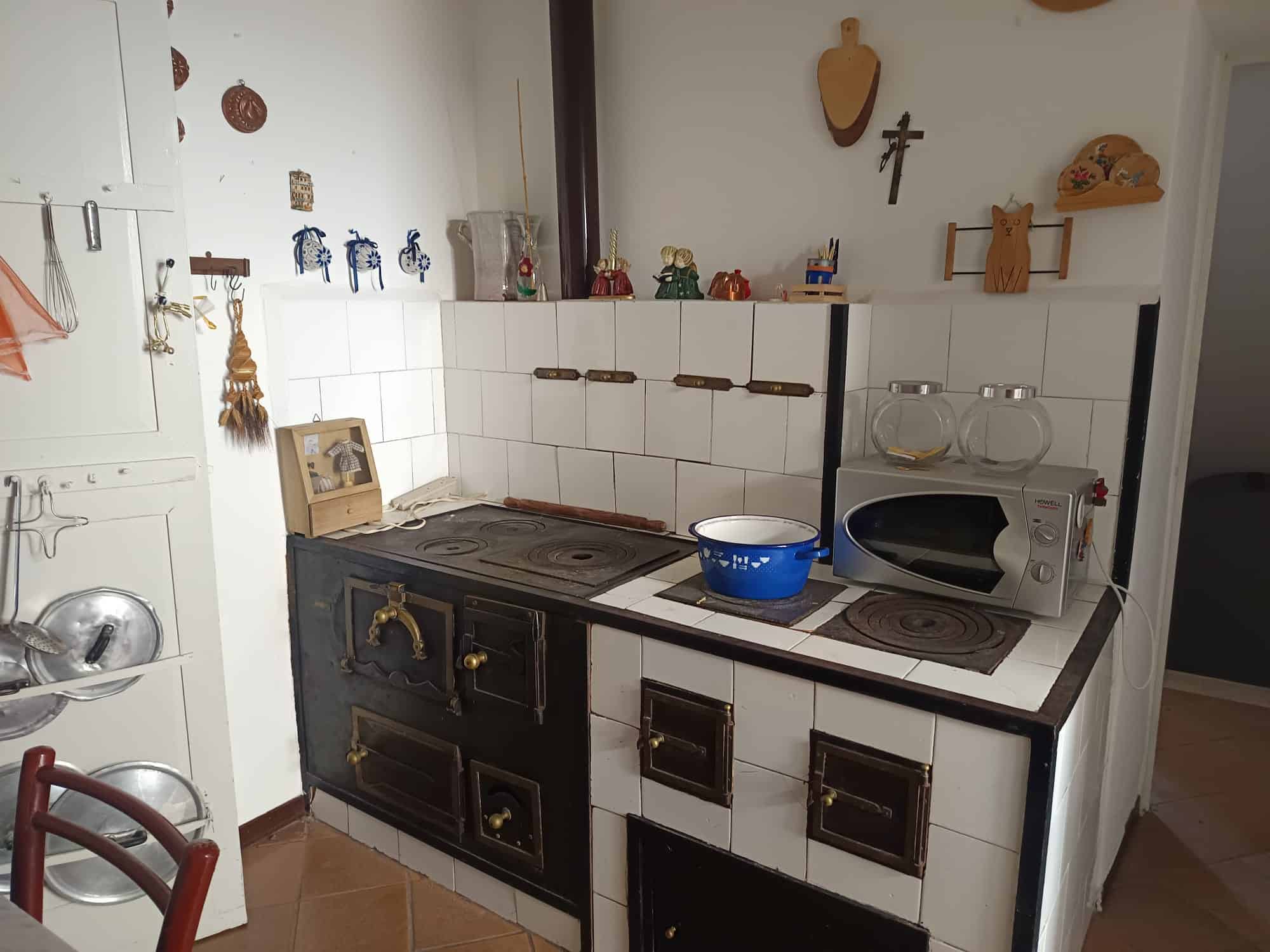 Pannello cucina tradizionale con forno e piano cottura in stile rustico, decorazioni artigianali e utensili vintage, ambiente accogliente e caratteristico.