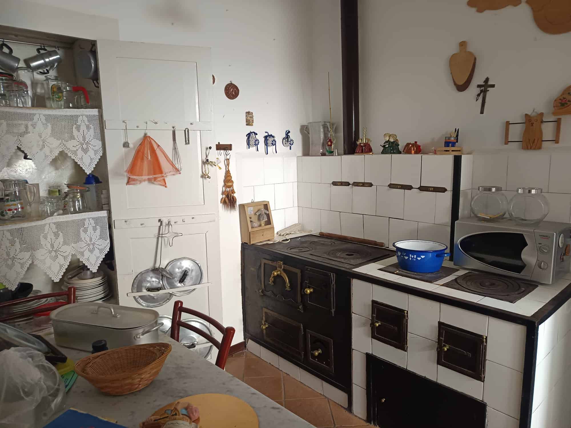 Antico camino in cucina con stoviglie e decorazioni tradizionali, ambiente accogliente e rustico, ideale per chi ama lo stile vintage e l'atmosfera casalinga. Perfetto per apprezzare la cucina tradizi.