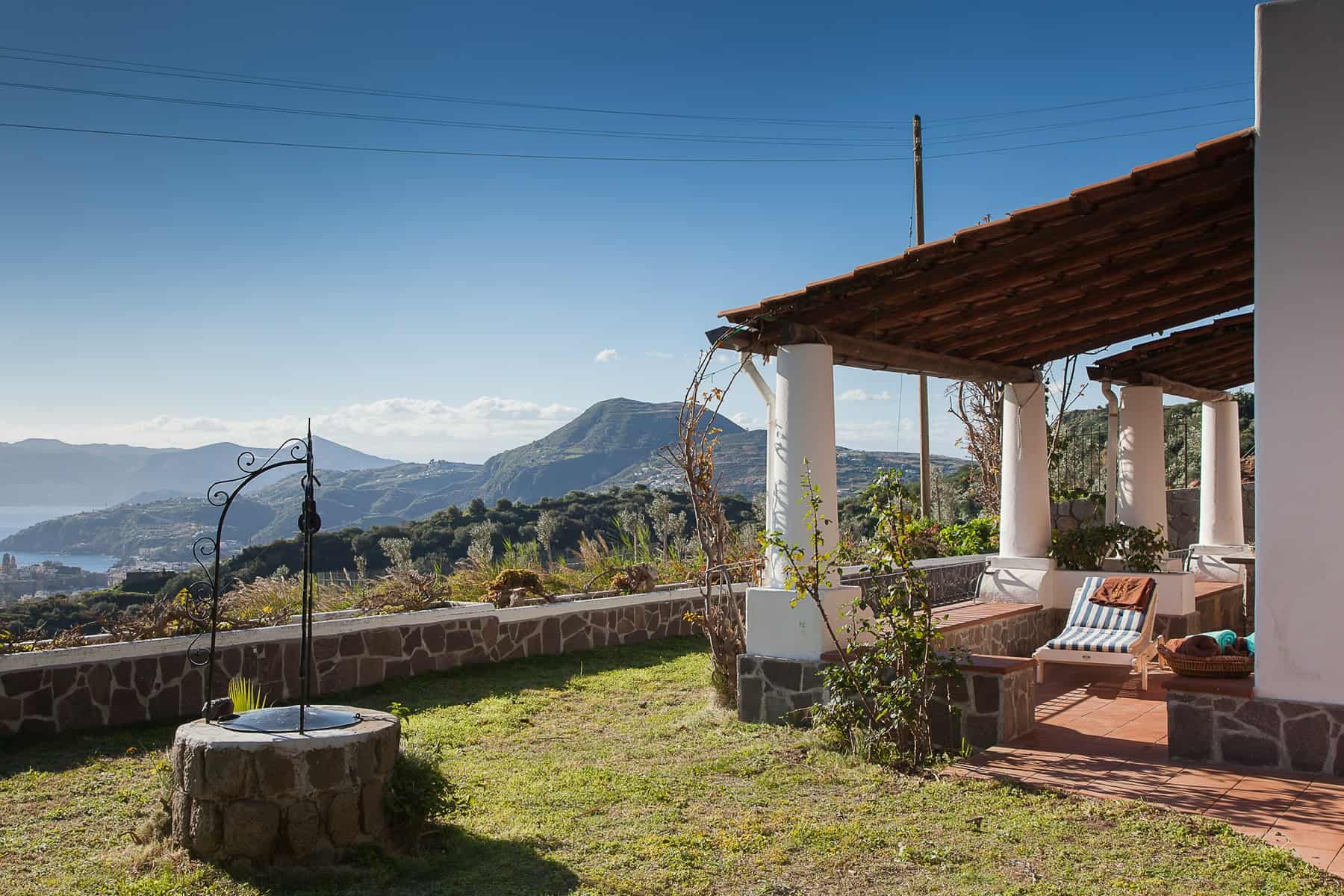 Vista panoramica di una casa di campagna con veranda e vista sulle montagne, ambiente tranquillo e rilassante, ideale per vacanze o soggiorni in natura in Italia.