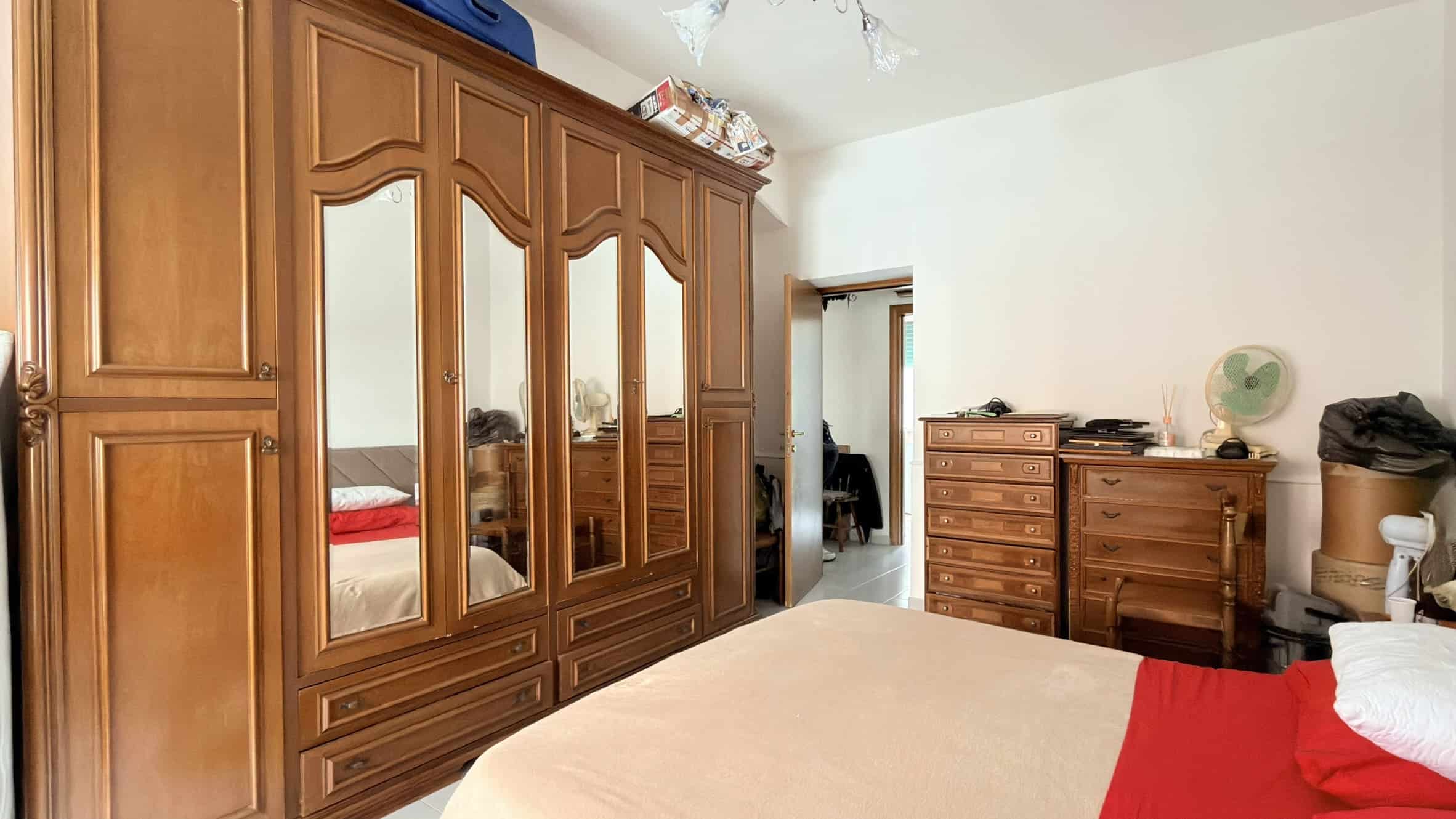 Armadio in legno massiccio con ante a specchio in una camera da letto spaziosa e luminosa.