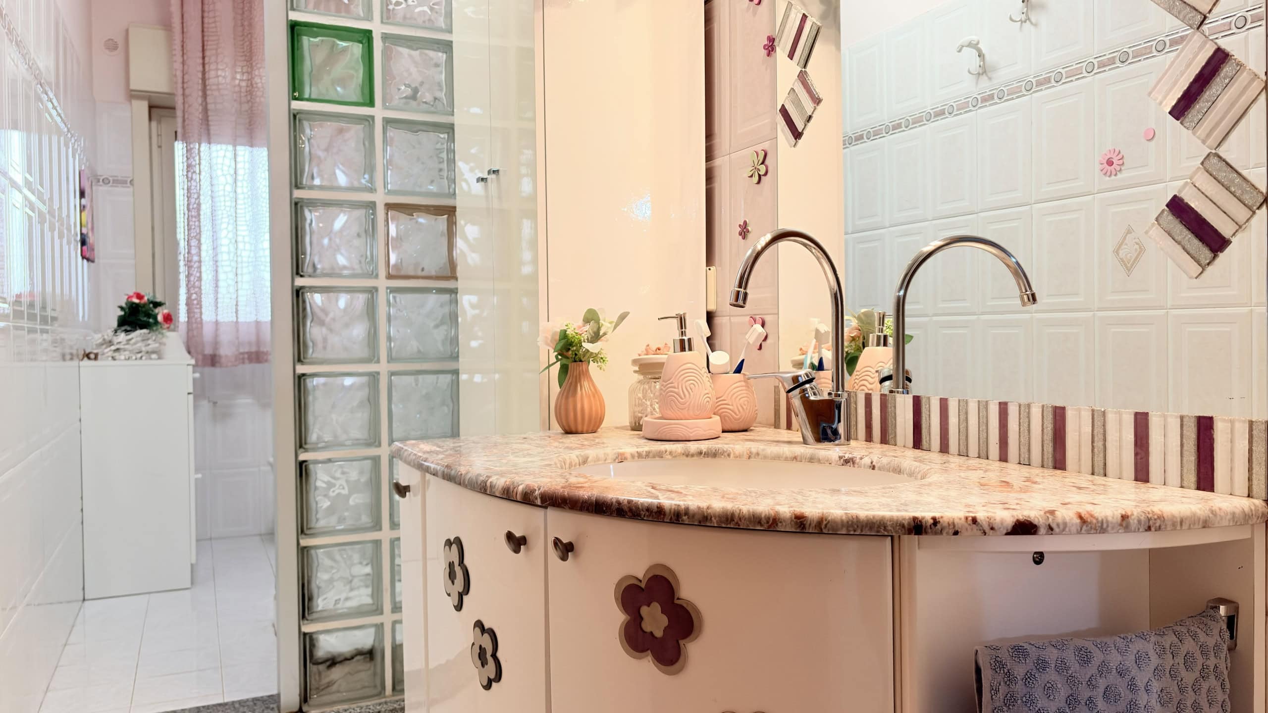Cucina moderna con piano in granito, lavelli doppi e decorazioni floreali, ambiente luminoso e accogliente.