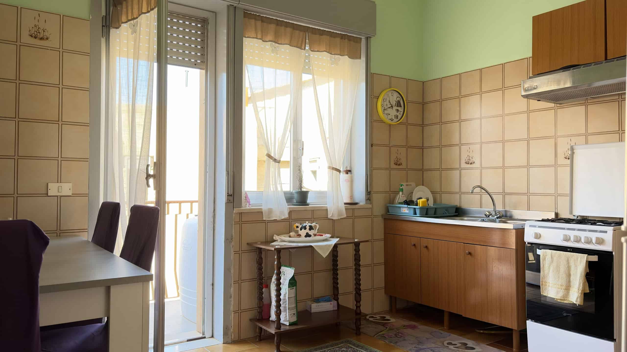 Lavastoviglie e cucina in stile classico in una cucina abitabile con pareti beige e finestra luminosa, ideale per case e appartamenti moderni.