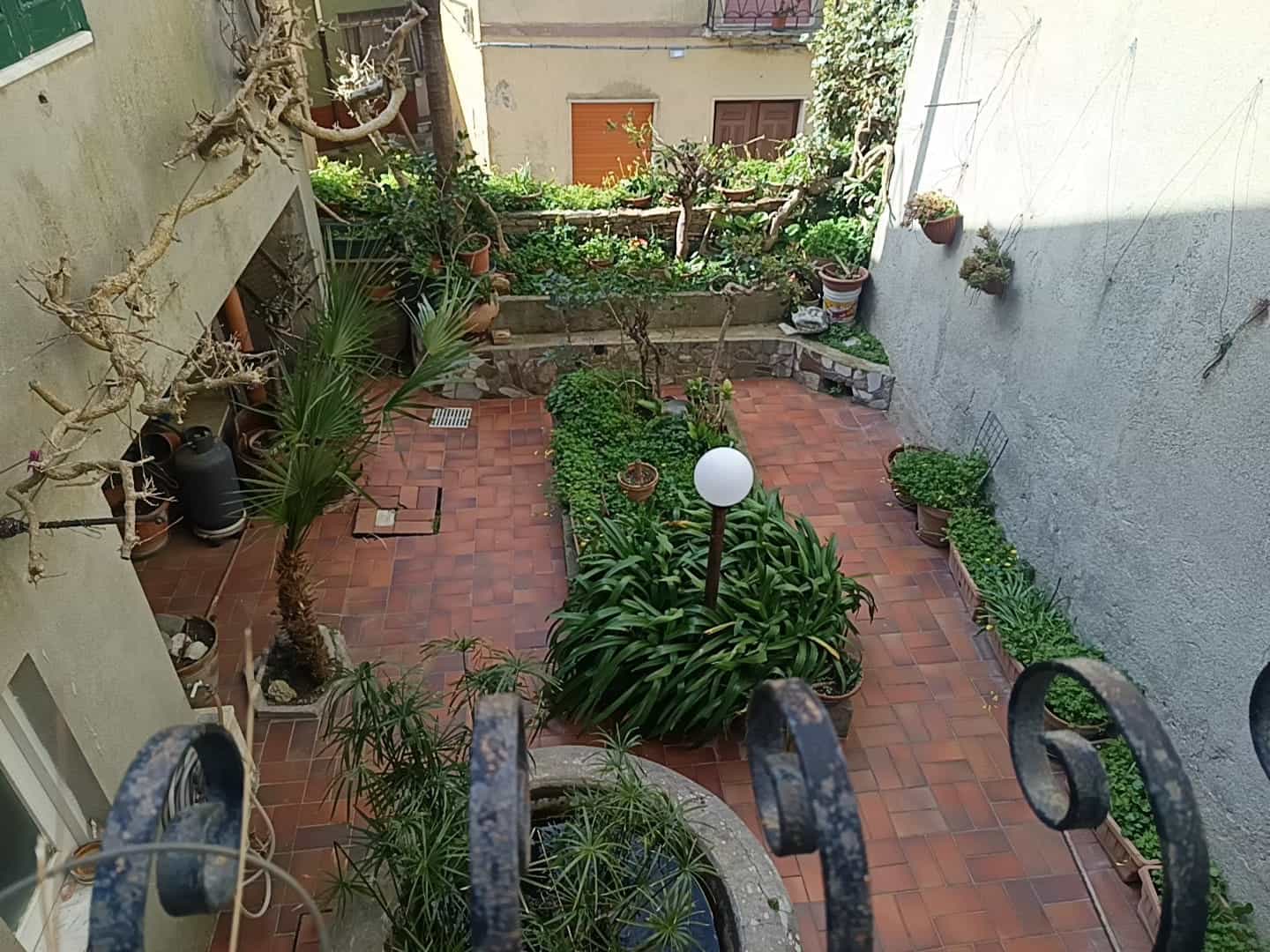 Piante verdi e giardino in cortile interno di casa con panchina e lampione, vista dall'alto.