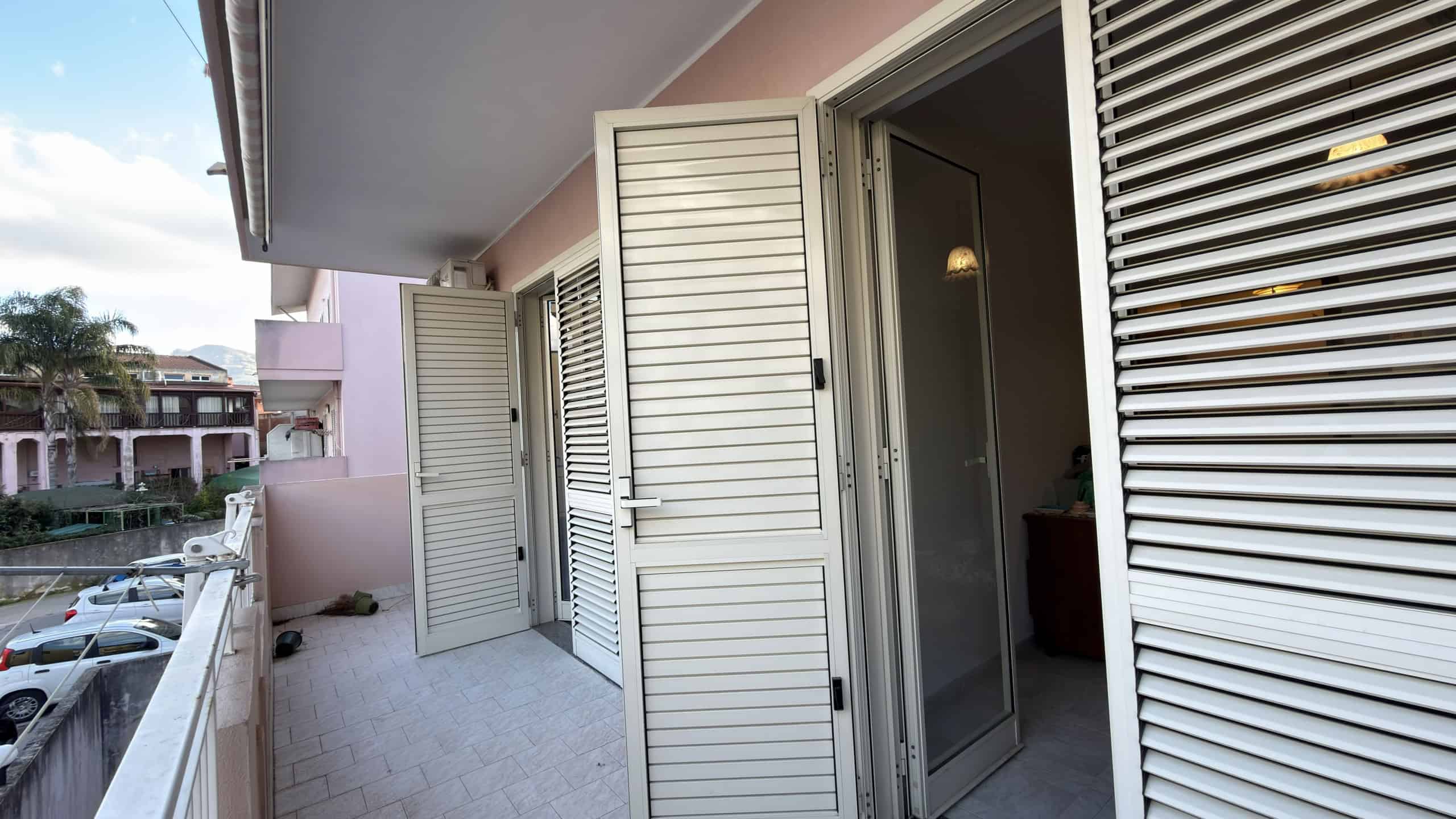 Porte blindate e finestre con persiane in alluminio su un balcone di un appartamento residenziale a NextCasa, ideale per sicurezza e isolamento termico.