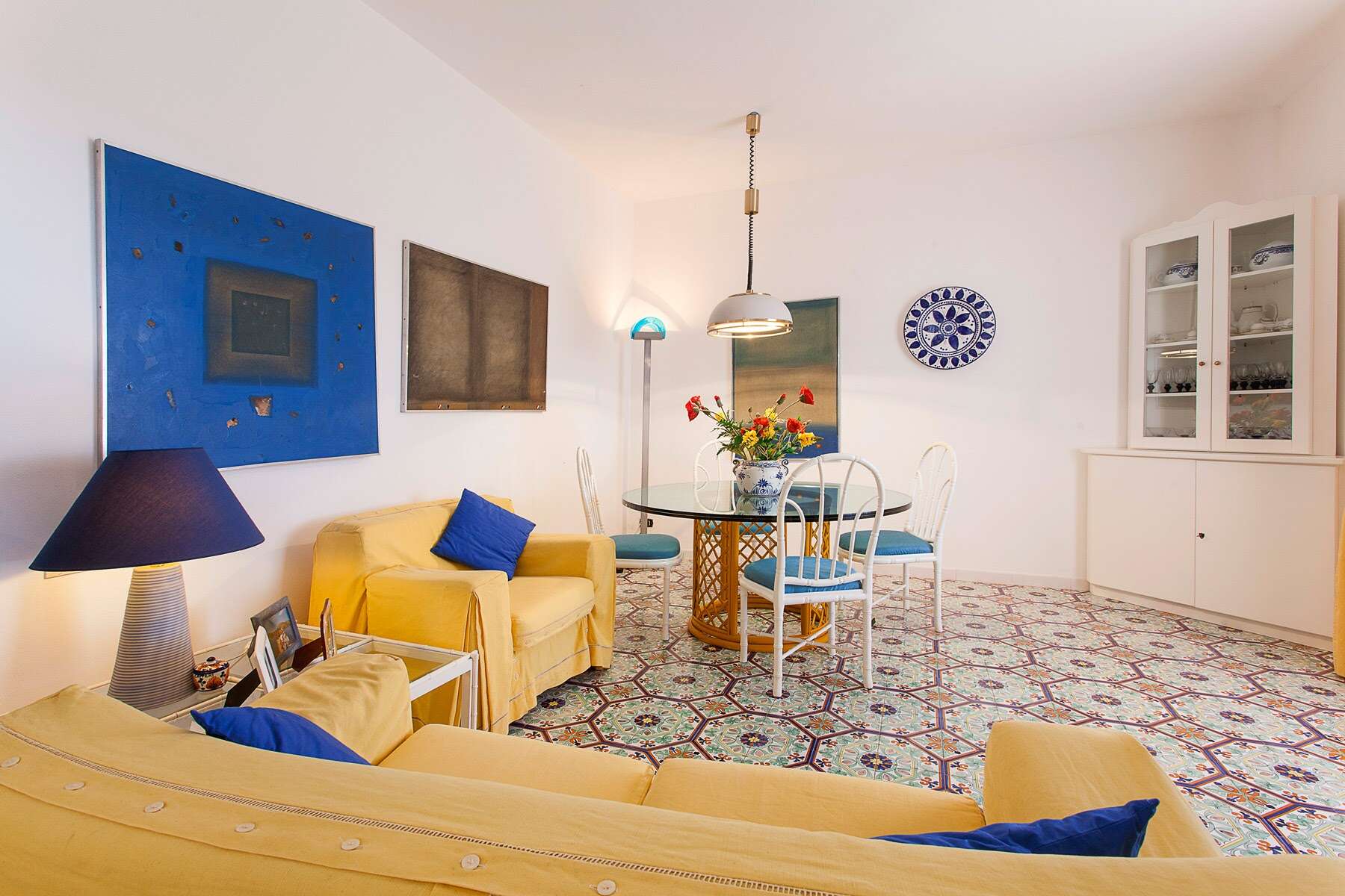 Il soggiorno luminoso con pareti bianche, divani gialli e decorazioni artistiche, ideale per vivere momenti di relax e convivialità.