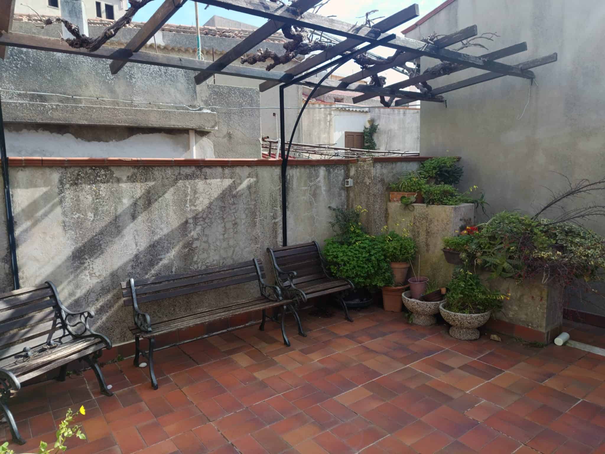Pannello solare e panchine in un cortile esterno con piante e decorazioni, spazio tranquillo e accogliente per relax e socializzazione all'aperto.