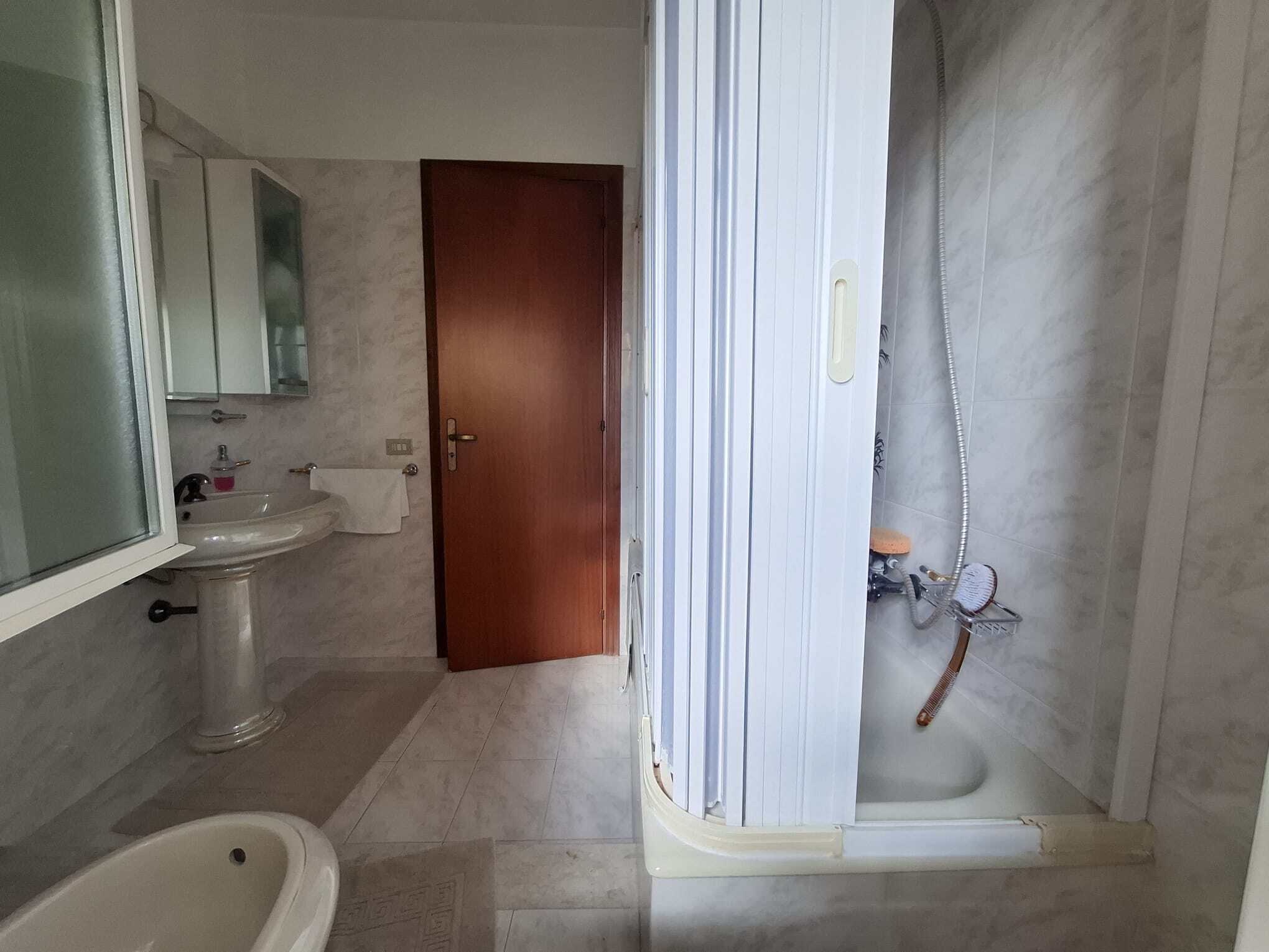 Lavabo e bagno con doccia in un appartamento in stile classico, con pareti in marmo e arredi funzionali, ideale per ristrutturazioni e miglioramenti domestici.