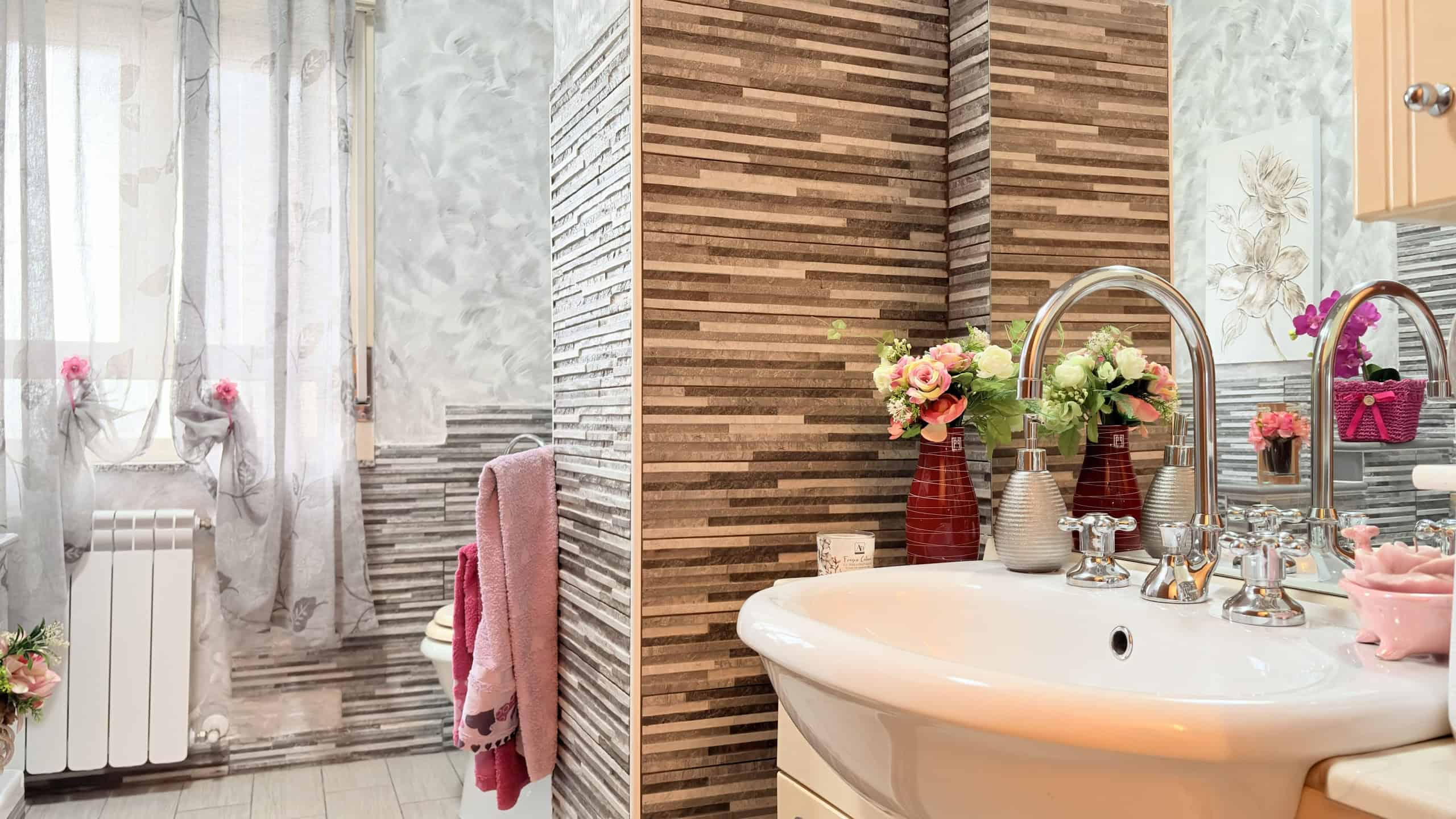 Lavabo moderno con piante e decorazioni floreali in un bagno elegante e luminoso.