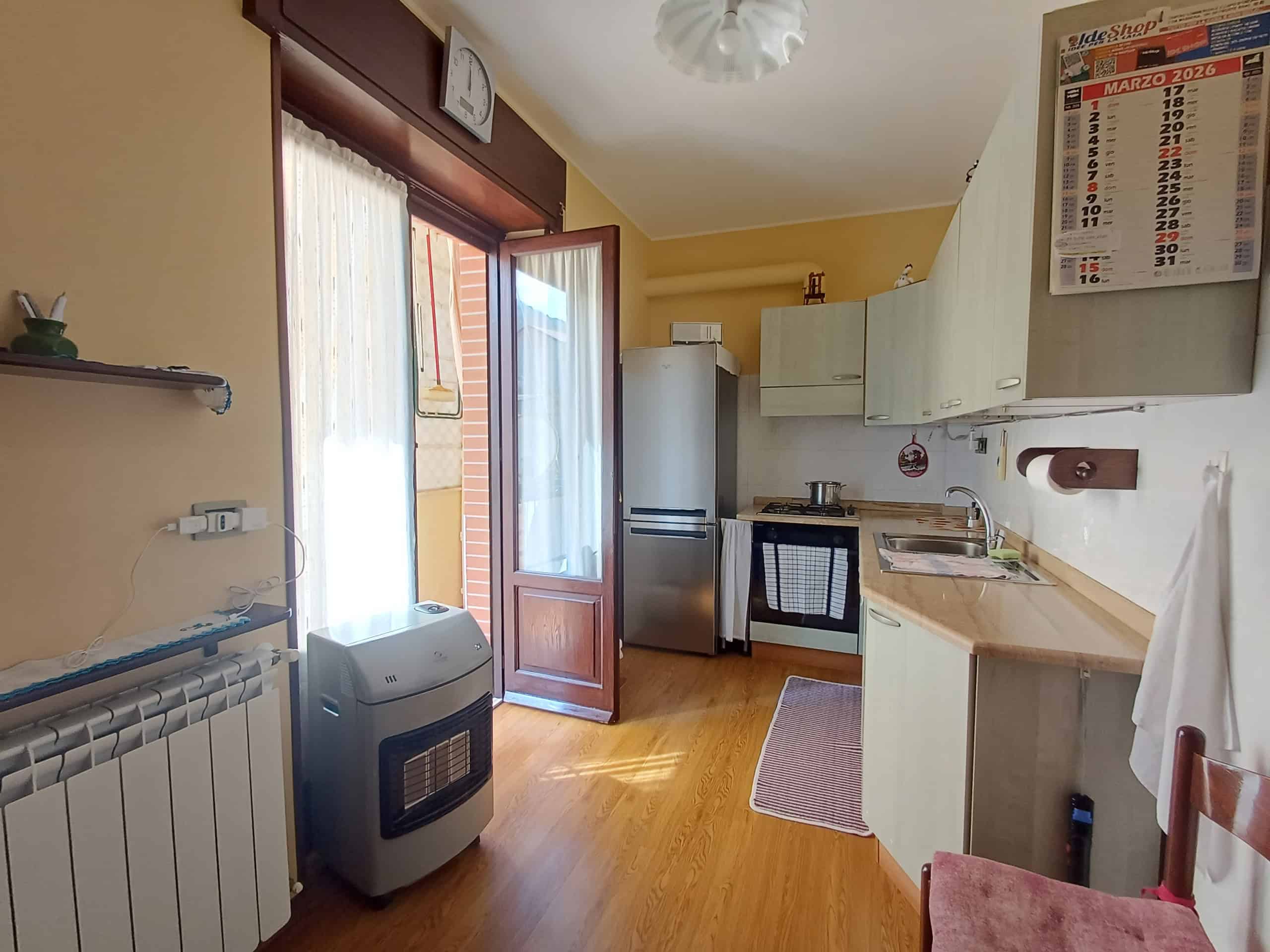 Pompa di calore portatile in cucina con accesso a balcone, arredamento funzionale e illuminazione naturale, ideale per riscaldare e raffreddare ambienti domestici in modo efficiente.