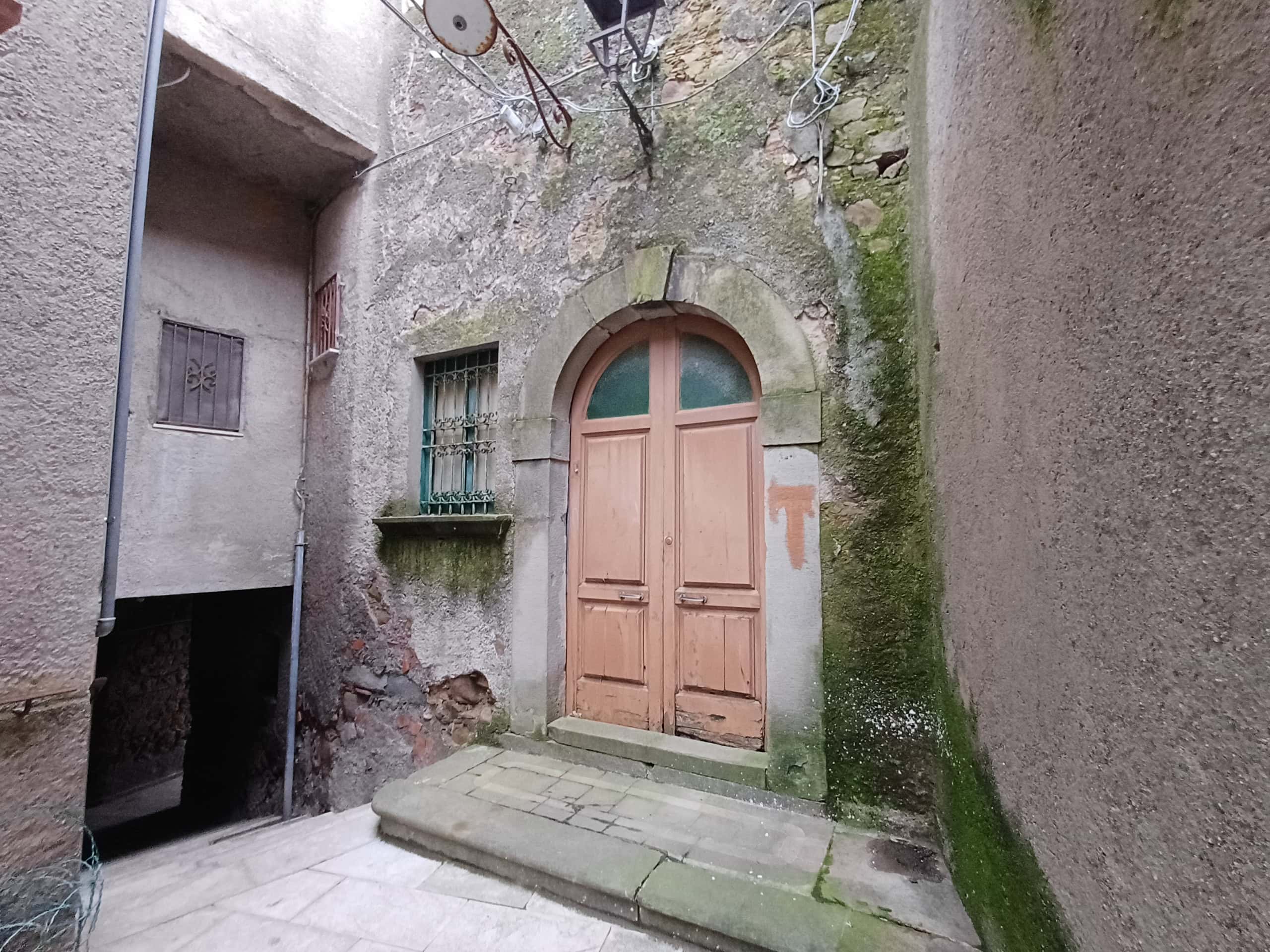 Anticamera di un edificio storico con porta in legno e pareti in pietra, mostra un ingresso caratteristico e suggestivo, ideale per valorizzare immobili di charme e proprietà con fascino antico.