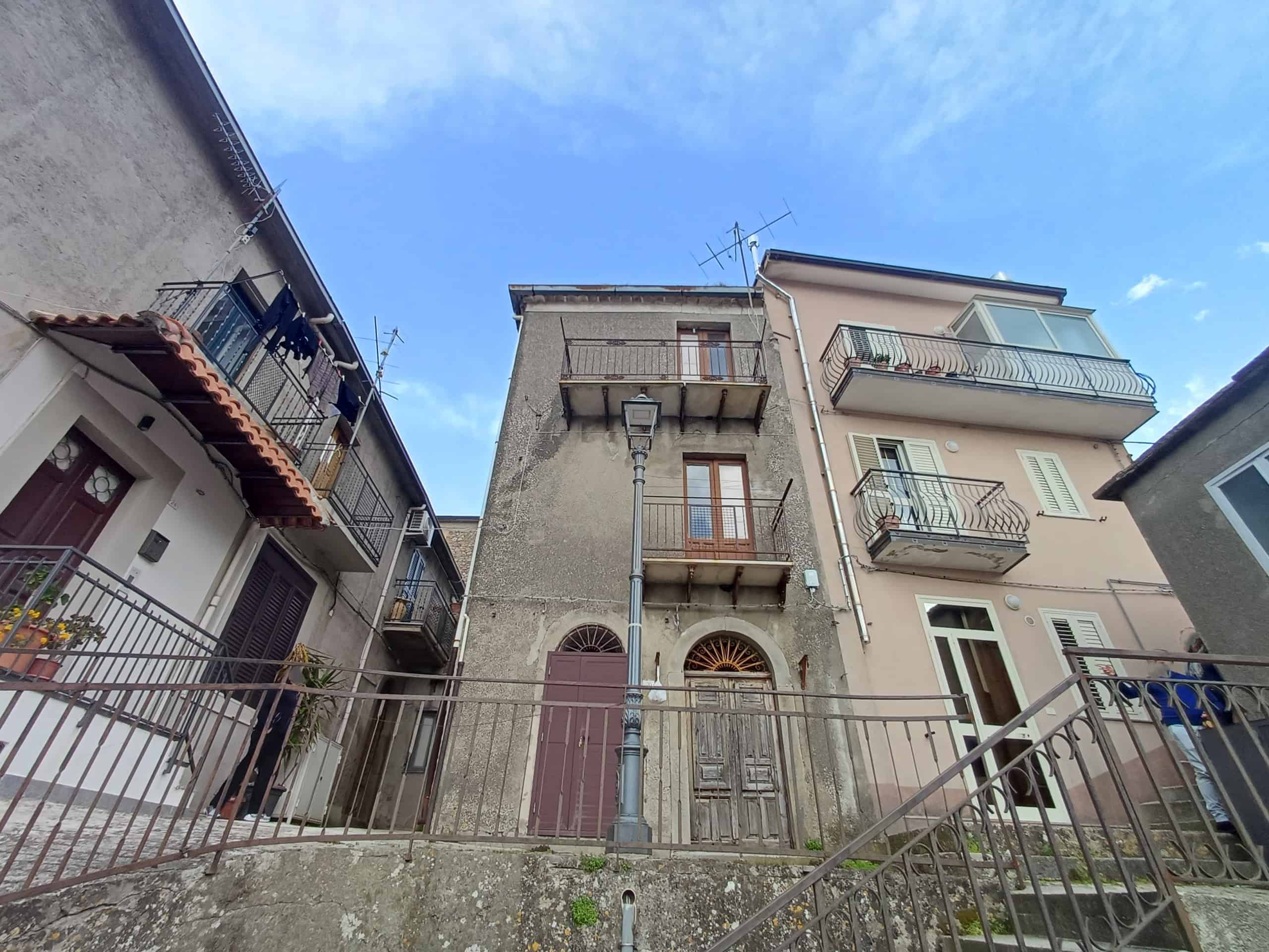 Edificio storico in centro città con balconi e facciata in pietra, vicino a strade pedonali e servizi, ideale per investimento immobiliare o residenza.