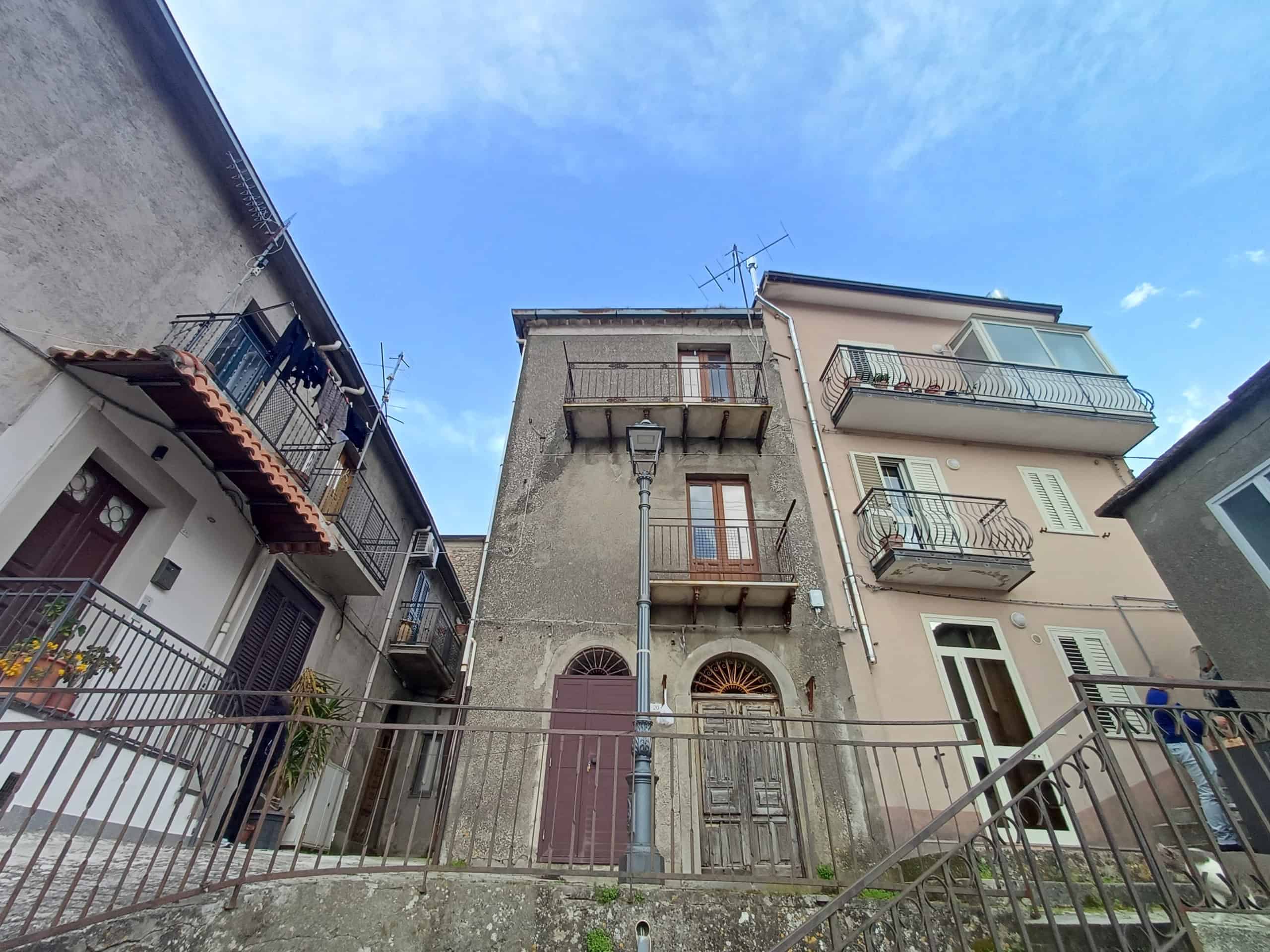 Edificio storico in centro città con facciata in pietra e balconi in ferro battuto, situato in una zona residenziale tranquilla vicino a servizi e trasporti pubblici.