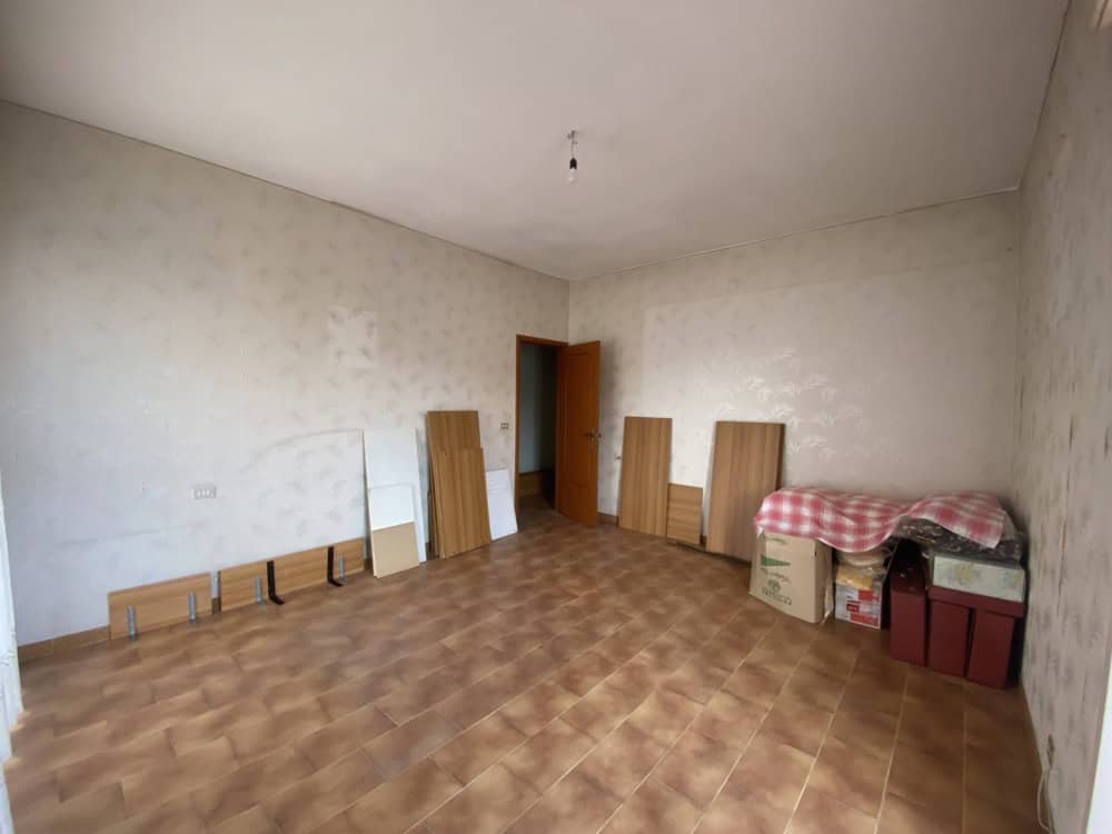 Pannello di pareti vuote e pavimento in piastrelle in una stanza da ristrutturare, con alcuni pannelli di legno e scatole di immagazzinaggio, pronta per essere personalizzata o rinnovata.