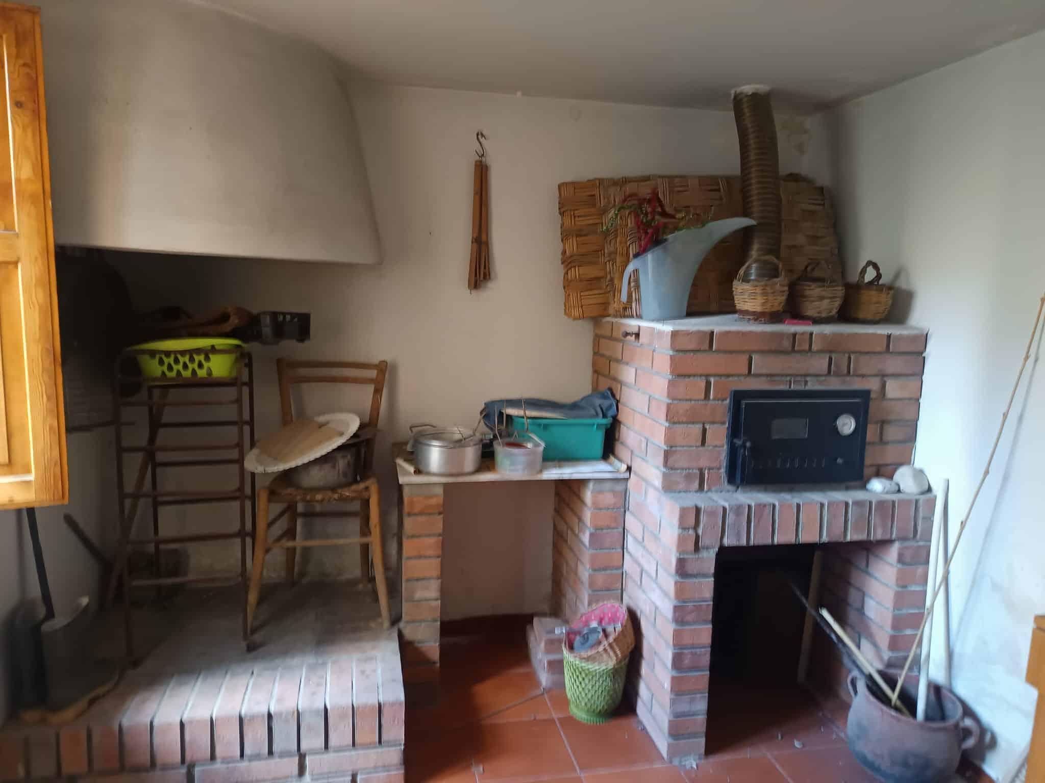 Panca in legno e camino in mattoni rossi in una cucina rustica con accessori tradizionali.