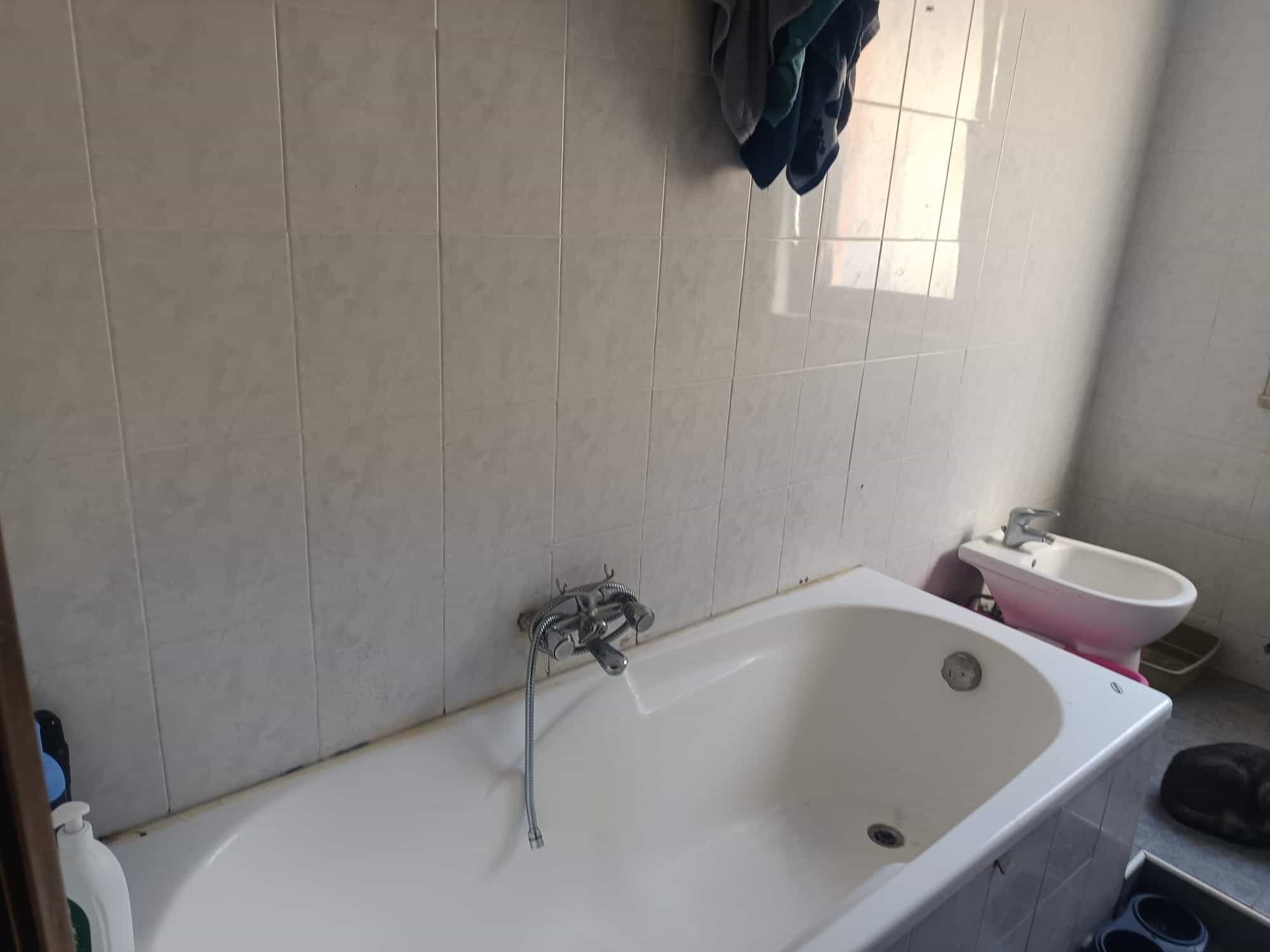 Lavandino da bagno con rubinetto e accessori, pareti rivestite in piastrelle chiare, ambiente pulito e ordinato, ideale per ristrutturazioni e arredo bagno.