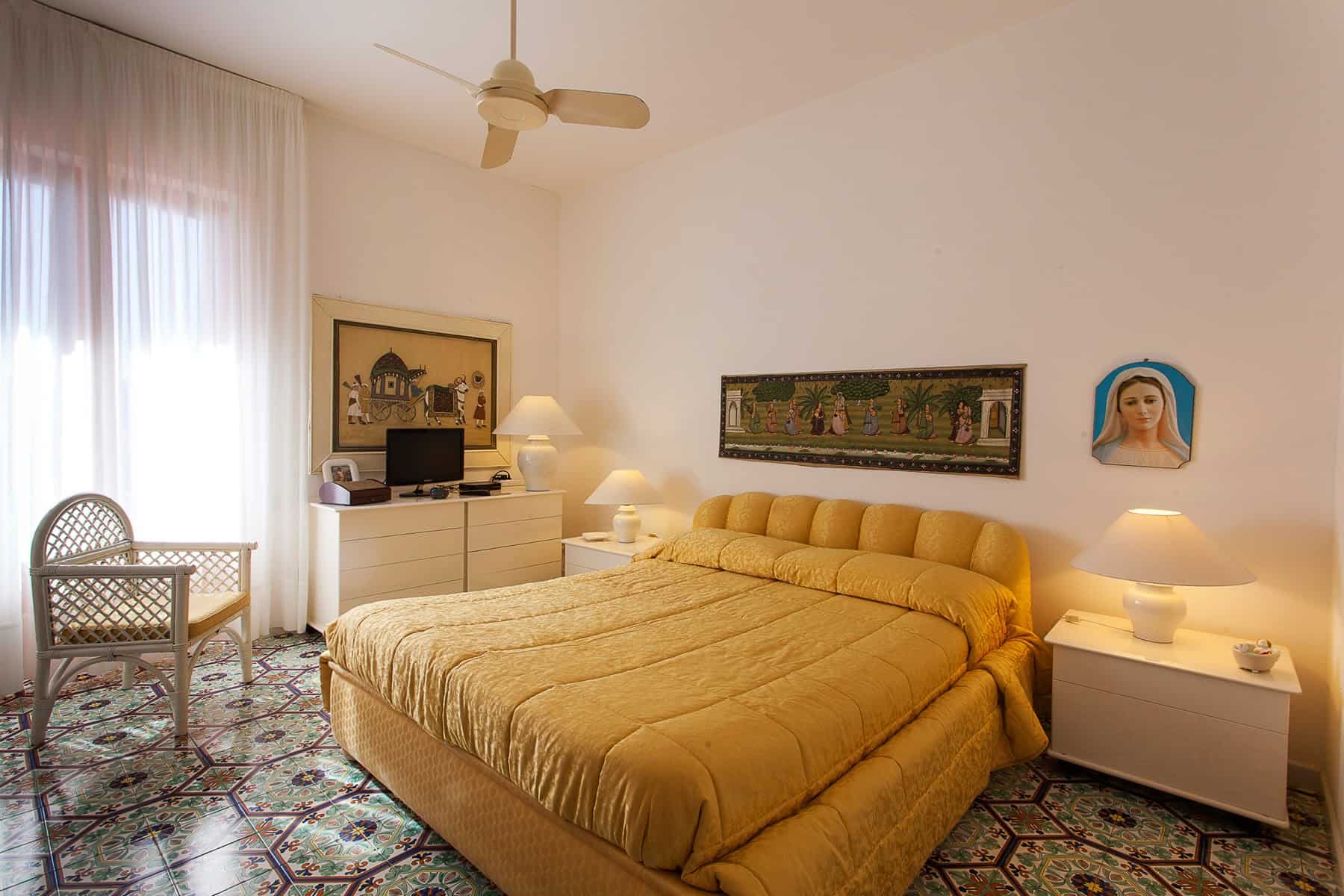 Una camera da letto luminosa con letto matrimoniale, tende trasparenti, decorazioni artistiche e mobili moderni, ideale per soggiorni confortevoli e rilassanti.