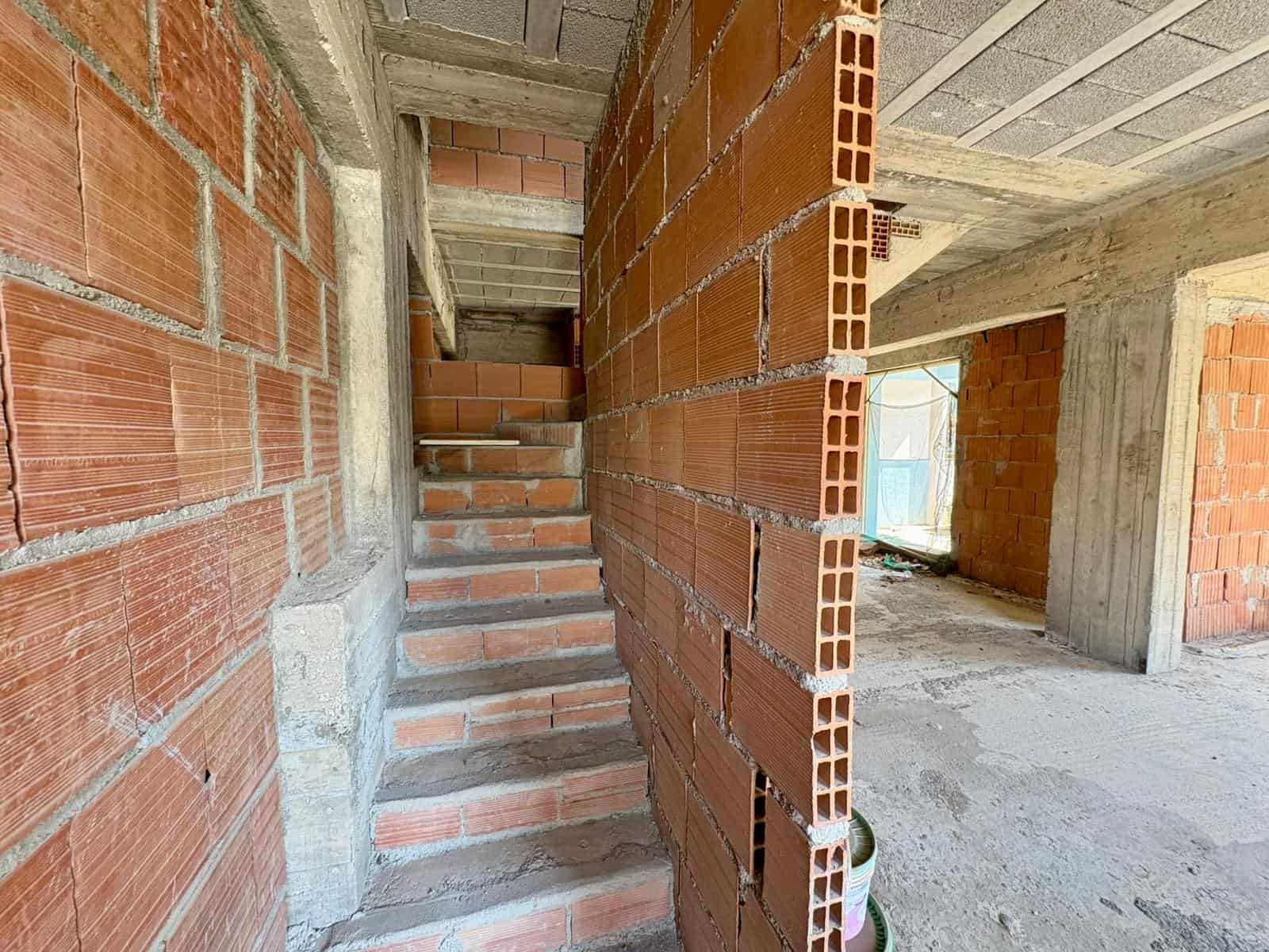 Cattura di un interno di edificio in costruzione con pareti in mattoni e scale in cemento, pronto per finiture e rifiniture. Ideale per progetti di ristrutturazione e nuove costruzioni residenziali o.