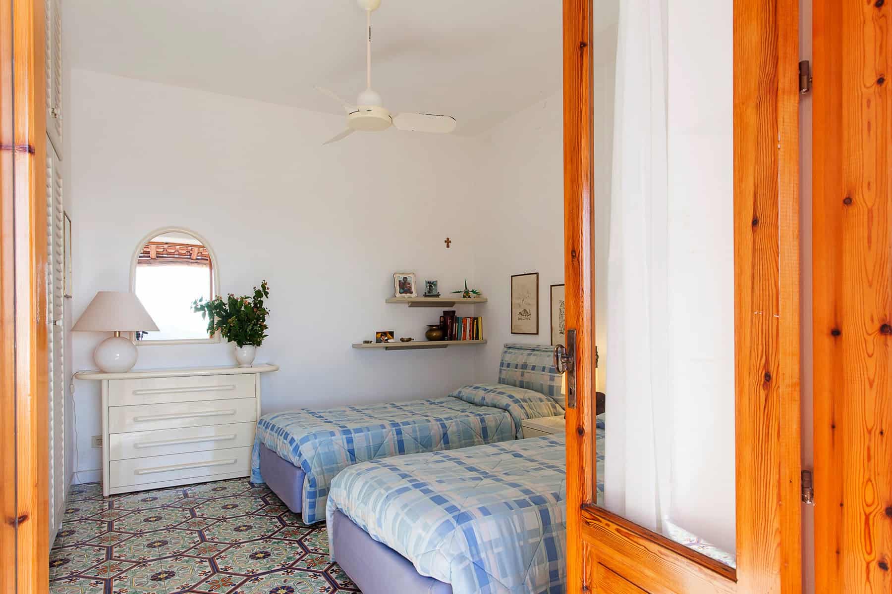Letto doppio in camera da letto con pareti bianche, arredi in stile classico, e decorazioni semplici, ideale per affitti turistici o case vacanza in Italia.