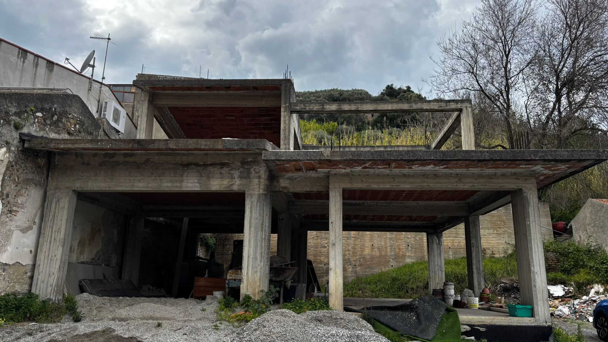 Pannello di costruzione in cemento e legno di una casa in fase di realizzazione, con struttura aperta e vista sul paesaggio circostante.