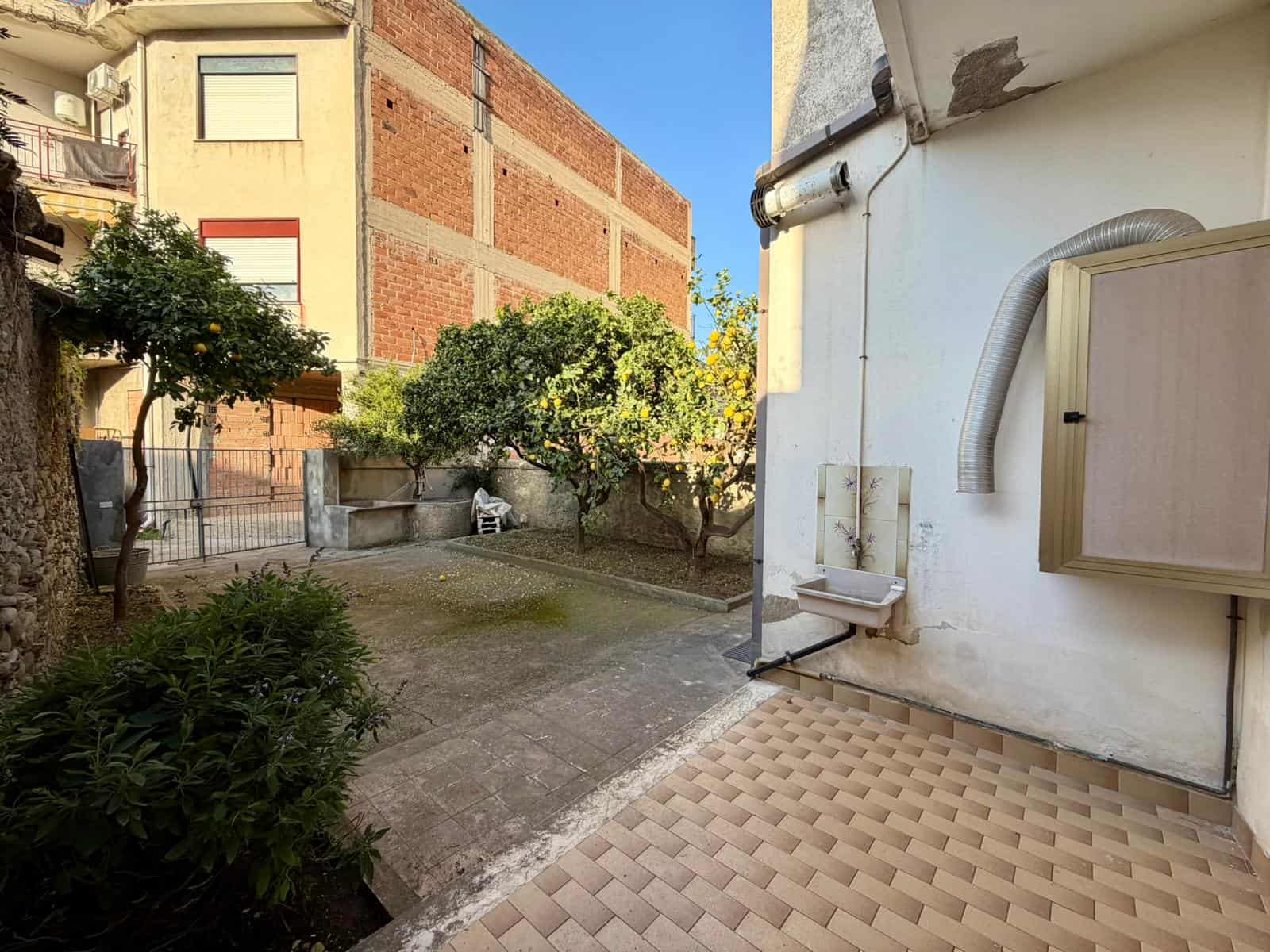 Balcone con vista sul cortile interno di un edificio residenziale, con piante e spazi aperti, in un contesto urbano italiano.