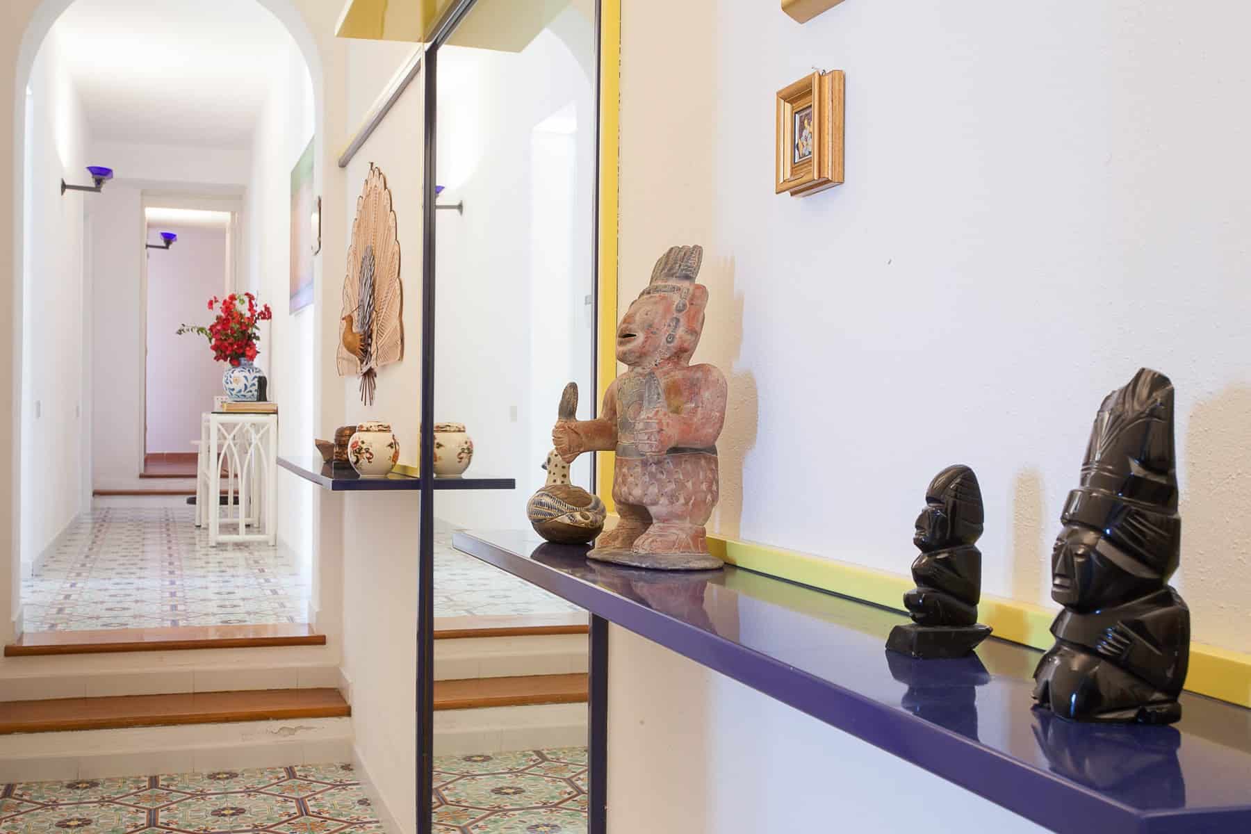 Anticrasti africani in ceramica e legno esposti su una mensola decorativa in un ambiente interno luminoso e accogliente.