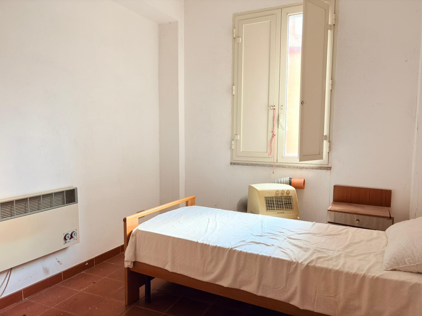 Letto singolo in camera semplice con finestra luminosa, arredamento minimale, ideale per affitti brevi o studenti, in un appartamento ben mantenuto.