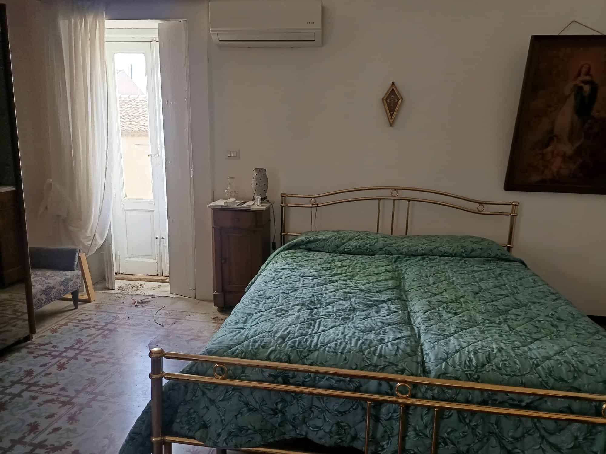 Letto matrimoniale con copriletto verde in una camera da letto luminosa e accogliente, con accessori eleganti e decorazioni artistiche. Perfetta per case in stile classico o moderno, ideale per chi ce.