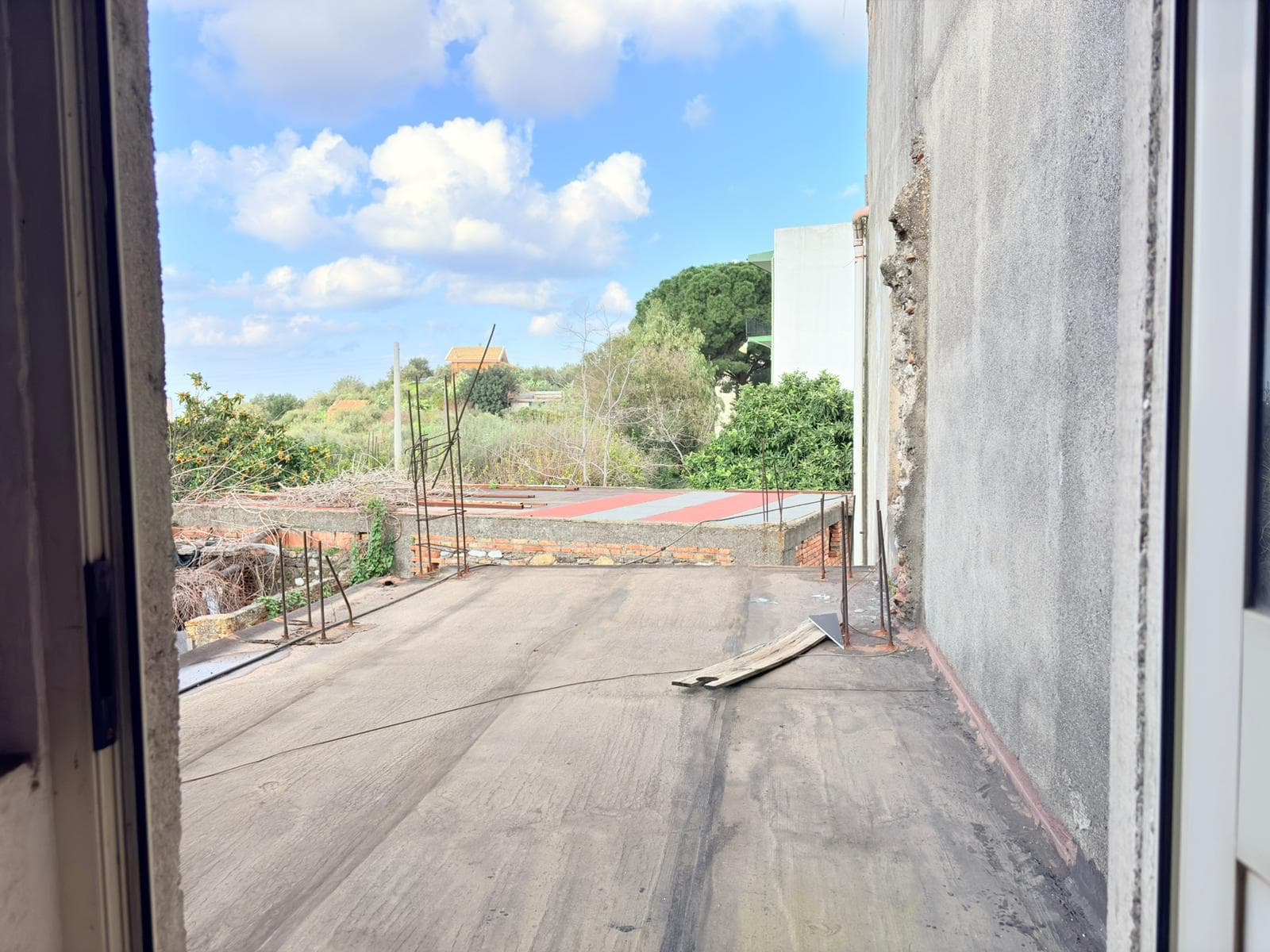 Aggiungi una vista panoramica di un balcone in fase di ristrutturazione con vista su un paesaggio verde e cielo sereno, ideale per immobili in costruzione o ristrutturazione.