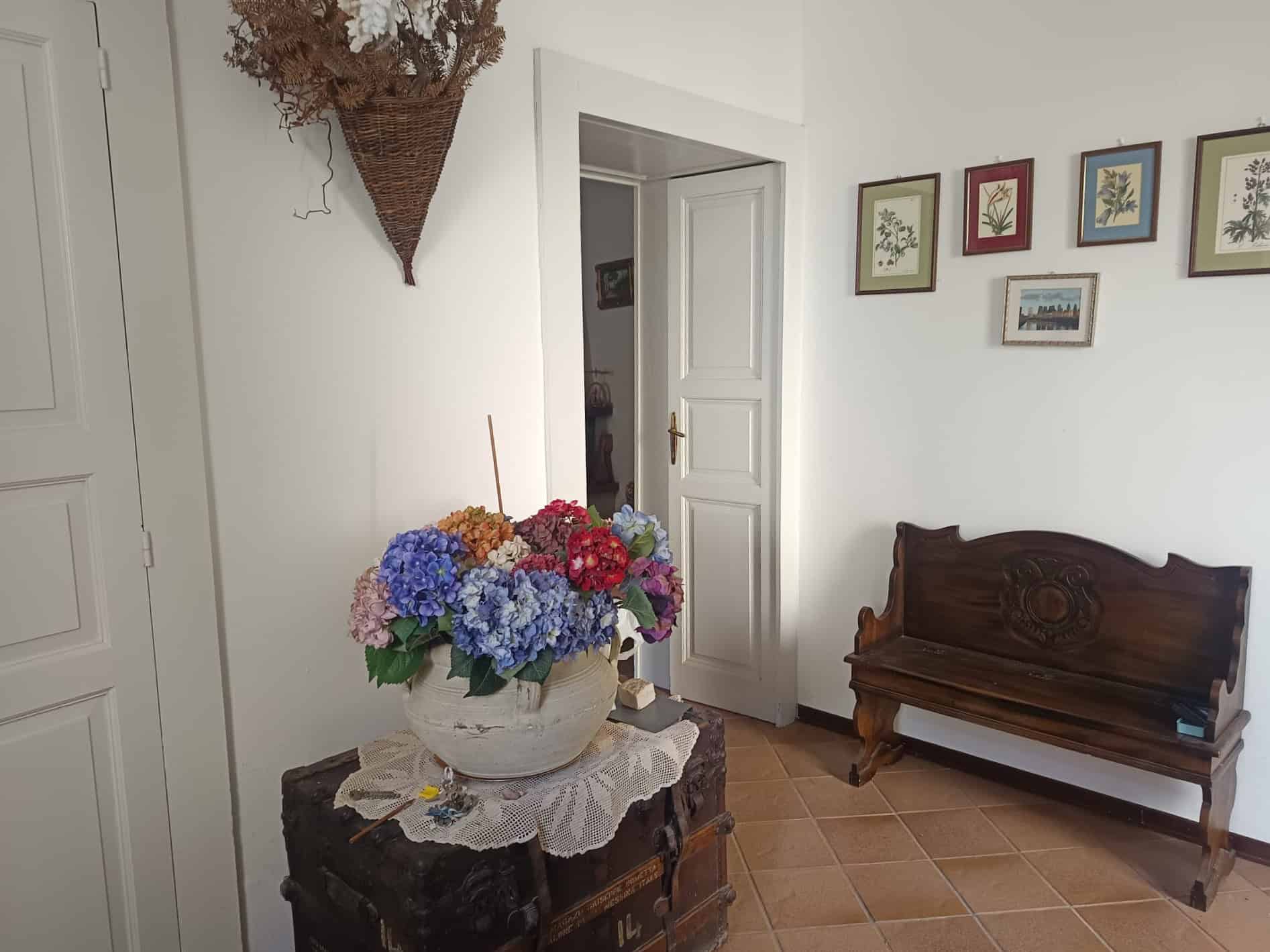 Mazzo di fiori colorati in vaso su tavolino in stile vintage in un soggiorno luminoso con pareti bianche e decorazioni floreali alle pareti.