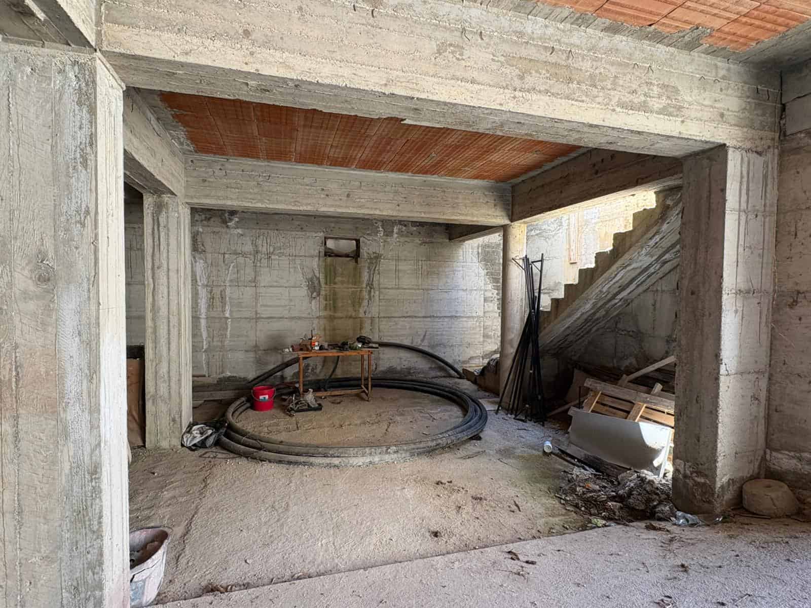 Interno di un edificio in costruzione con struttura in cemento armato, pronto per lavori di finitura e installazioni future.