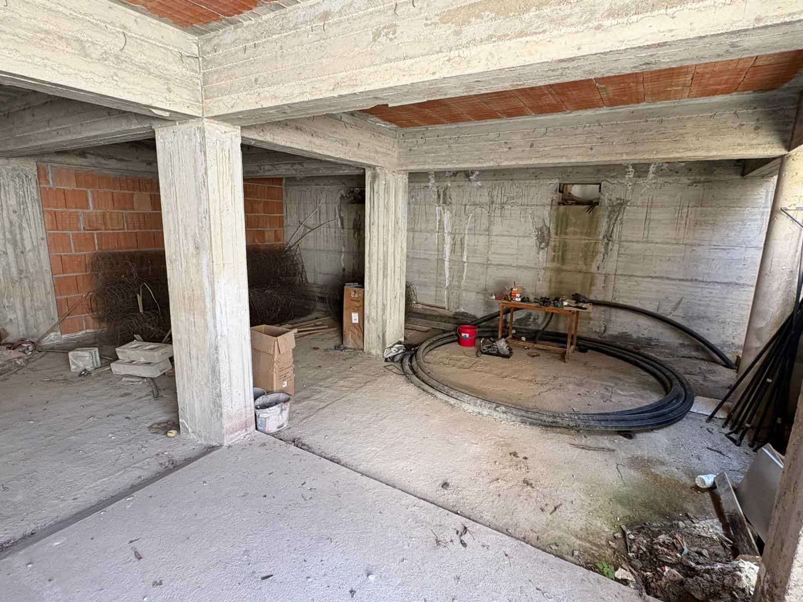 Interno di un edificio in costruzione con strutture in cemento e mattoni, pronto per lavori di finitura e impianti tecnici.