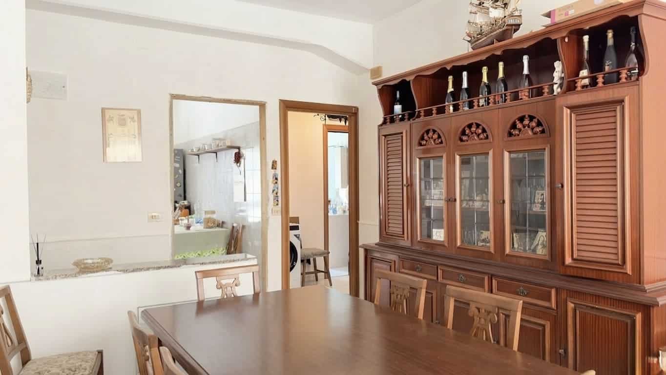 Antistante di una sala da pranzo con tavolo in legno e sedie, arredamento classico in stile tradizionale, grande credenza in legno con vetrine e decorazioni, ambiente luminoso e accogliente.