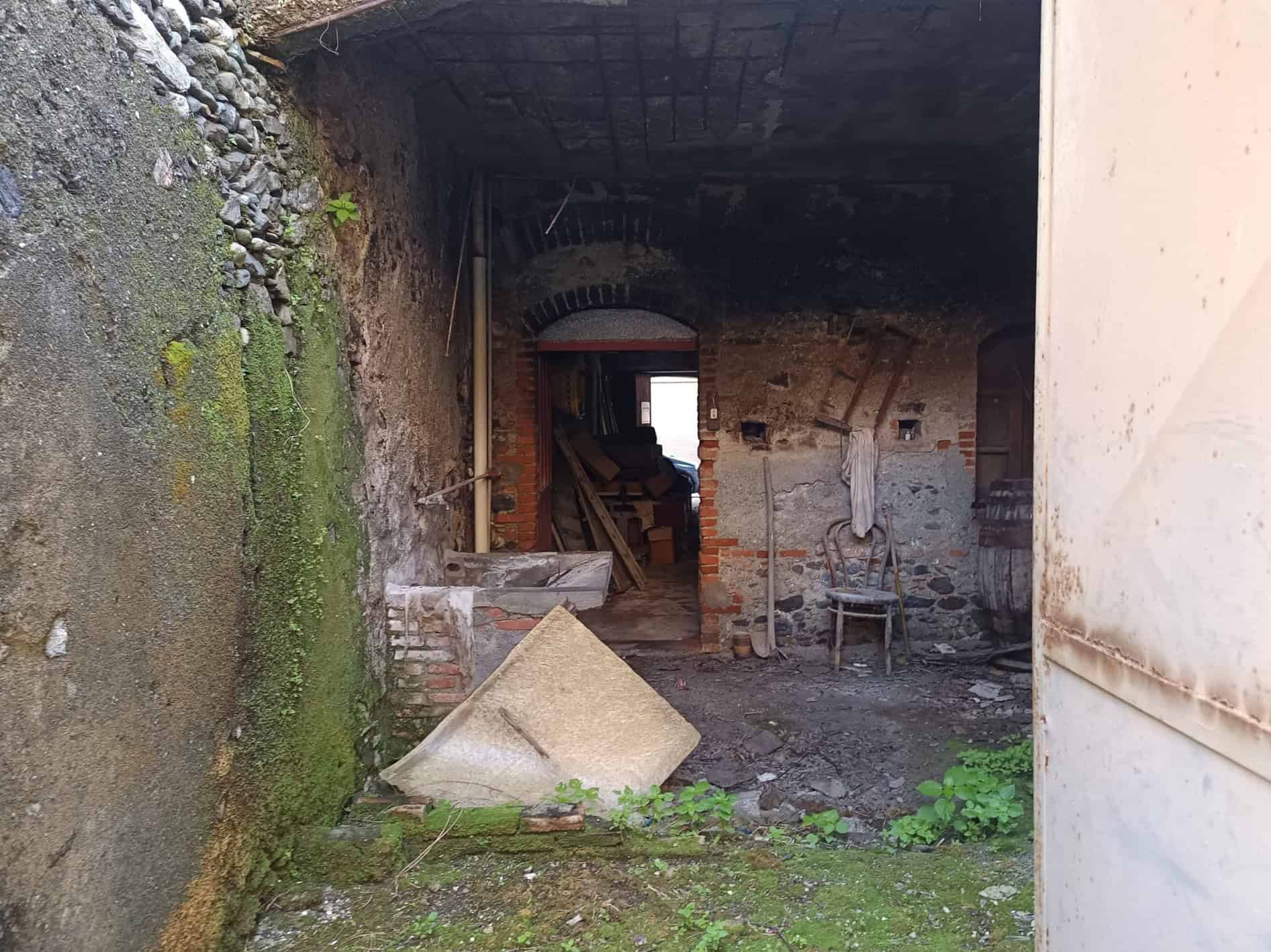 Spazio interno di una proprietà in ristrutturazione con muri in pietra e mattoni, area di lavoro abbandonata, ideale per progetti di ristrutturazione e restauro.