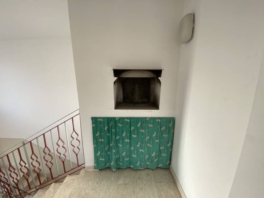 Il forno a legna in una casa moderna con pareti bianche e un rivestimento decorativo verde con motivi floreali. Ideale per cucinare pizza e pane in un ambiente accogliente e funzionale.