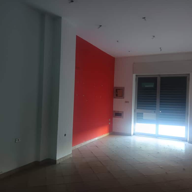 Pannello di parete rossa in un soggiorno luminoso con grande finestra e pavimento in piastrelle, pronto per l'arredamento.