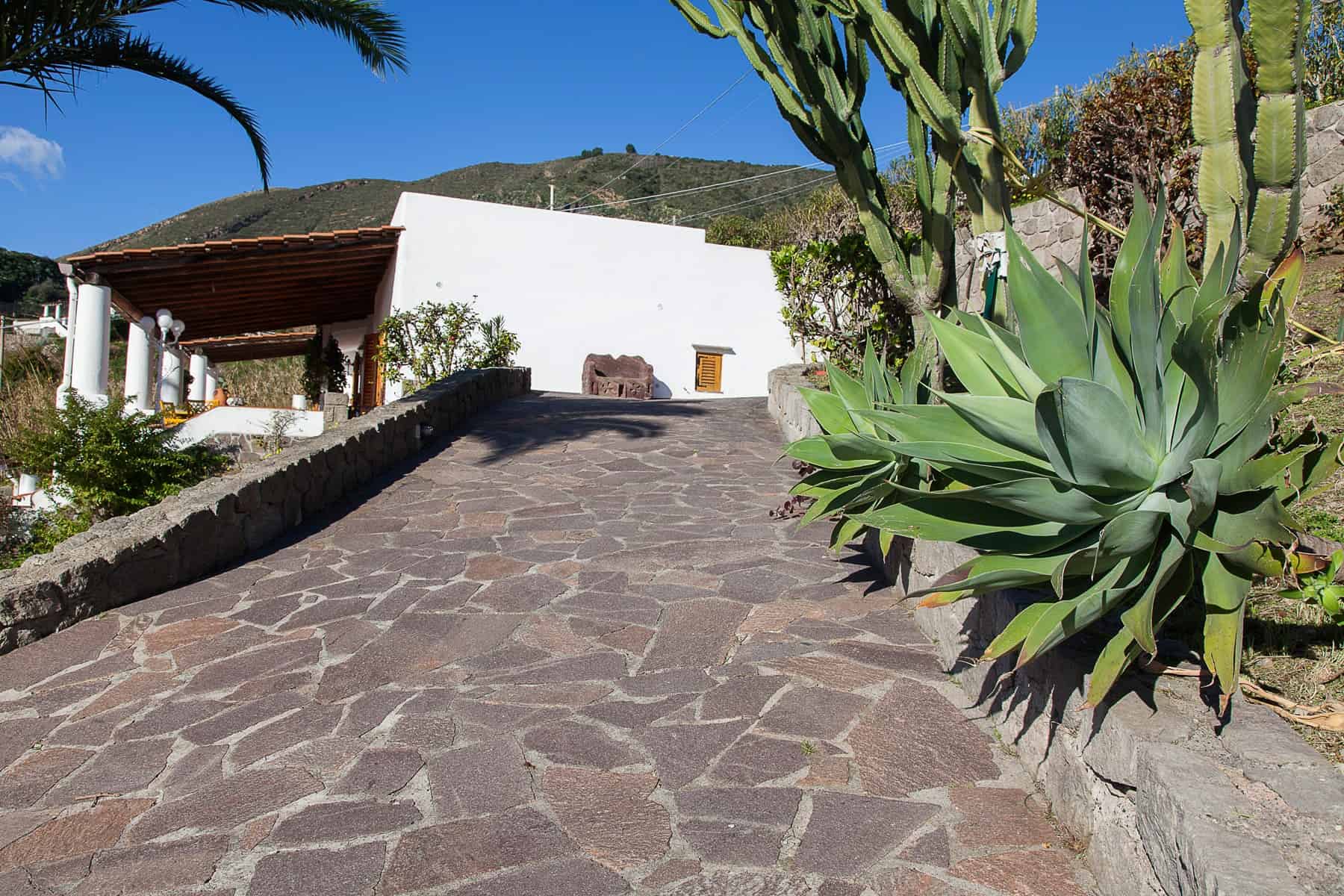 Porte di accesso in pietra naturale a una casa di campagna con giardino mediterraneo, vista panoramica sulle colline e ambiente esterno accogliente e rustico.