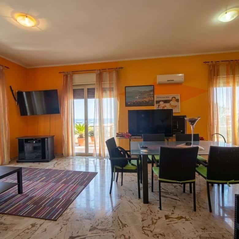 Ampio soggiorno luminoso con grandi finestre, arredi moderni e accessori eleganti, ideale per vivere e rilassarsi in un ambiente confortevole e accogliente.