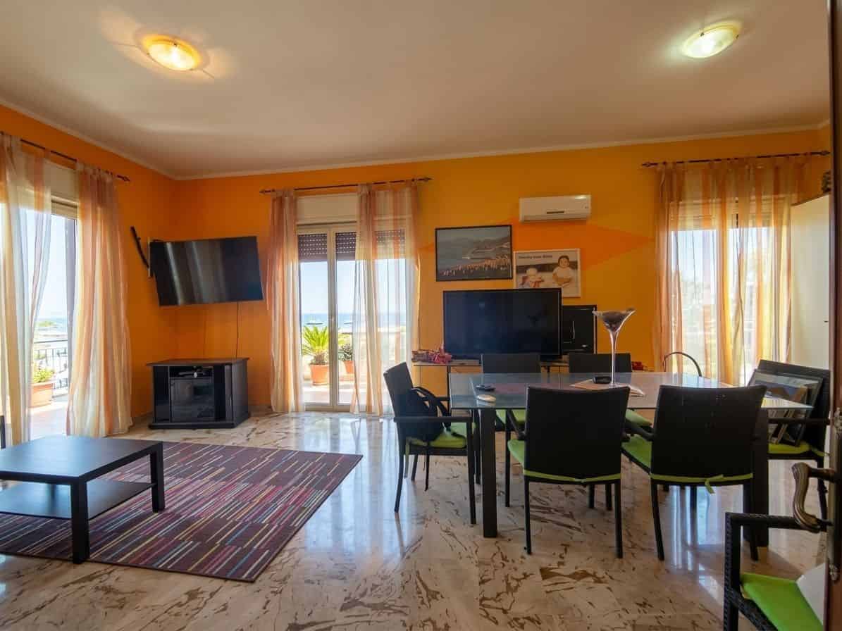Ampio soggiorno luminoso con grandi finestre, arredi moderni e accessori eleganti, ideale per vivere e rilassarsi in un ambiente confortevole e accogliente.