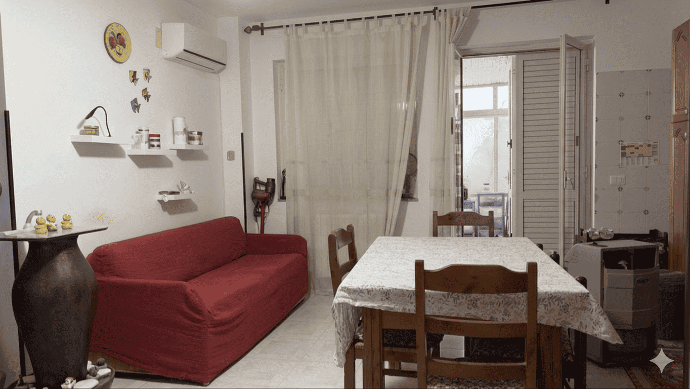 Soggiorno accogliente con divano rosso, tavolo da pranzo e decorazioni moderne in un ambiente luminoso e ben arredato. Ideale per vivere momenti di relax e convivialità in casa.