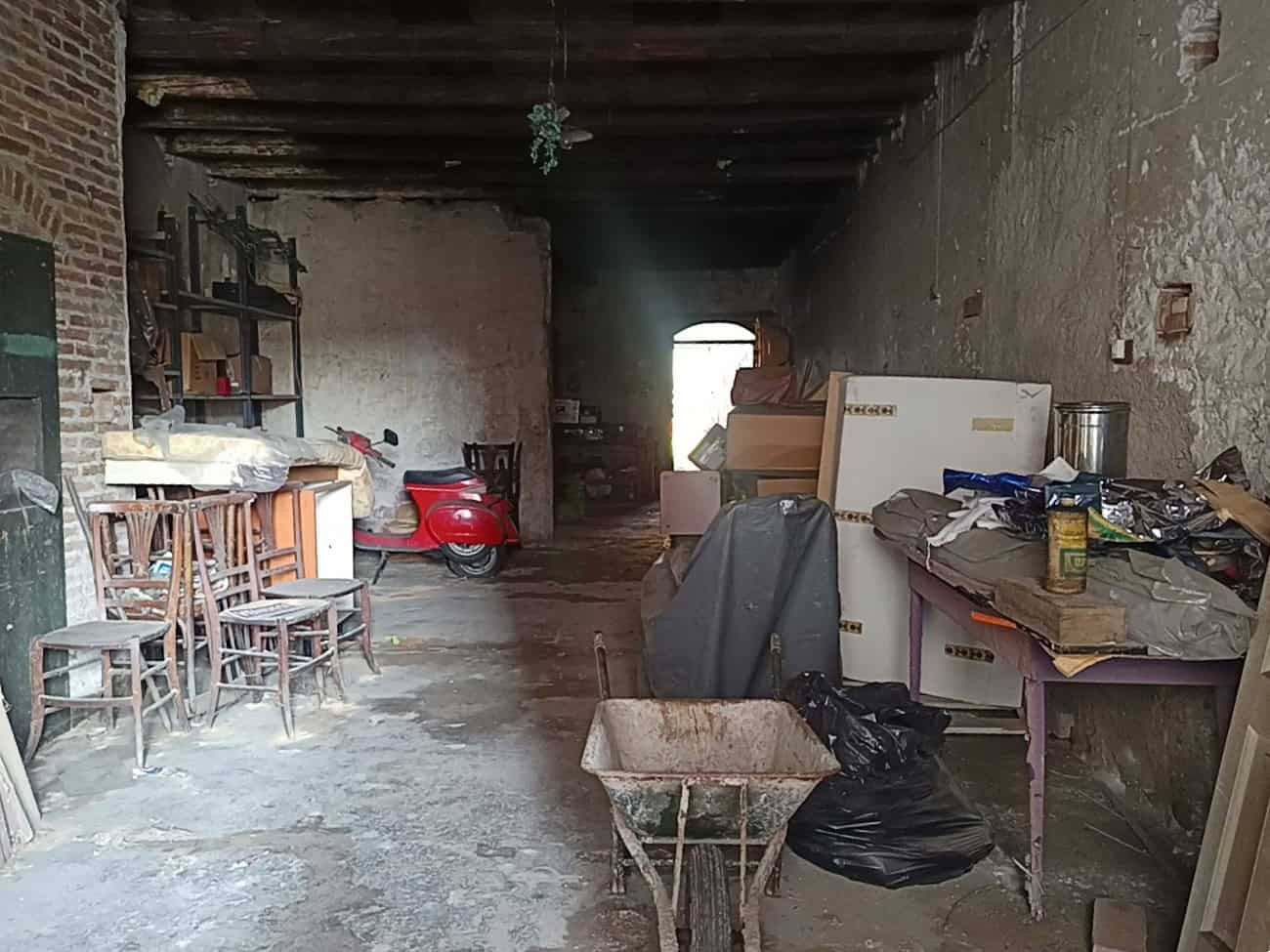 Porte di un magazzino o soffitta disorganizzata con mobili, scatole e oggetti vari, ambiente rustico e trascurato, ideale per immagini di ristrutturazione o stoccaggio.