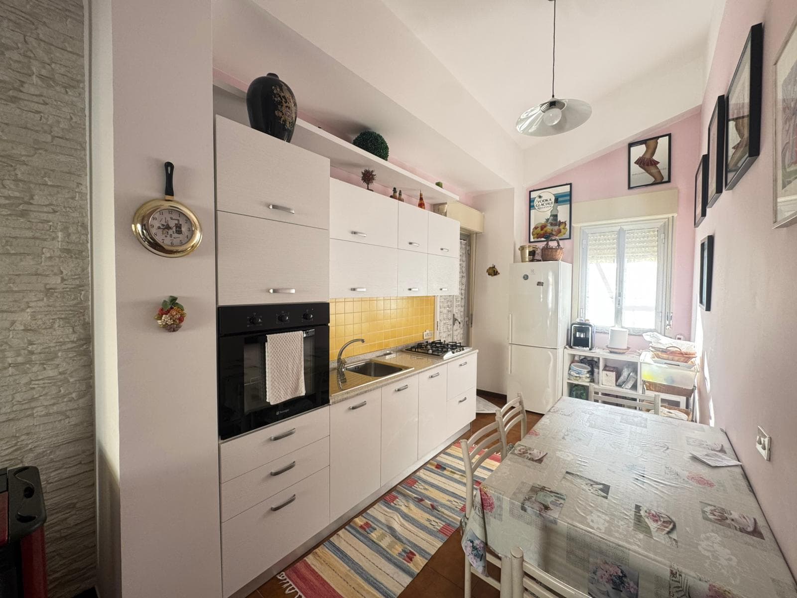 Lavagna da cucina moderna con mobili bianchi, piano di lavoro in acciaio e dettagli decorativi, in un ambiente luminoso e accogliente.