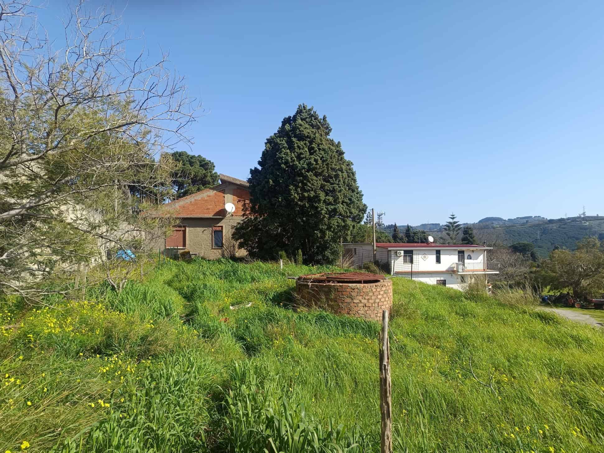 L'immagine mostra un paesaggio rurale con case, alberi e un'area verde rigogliosa, ideale per chi cerca immobili immersi nella natura in Italia.