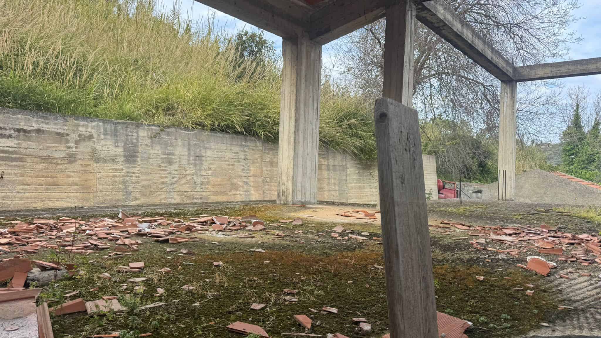 Scavo del terreno con strutture in cemento e mattoni rotti, pronto per la costruzione di una nuova casa o progetto edilizio, immerso nel verde e in un'area di cantiere all'aperto.