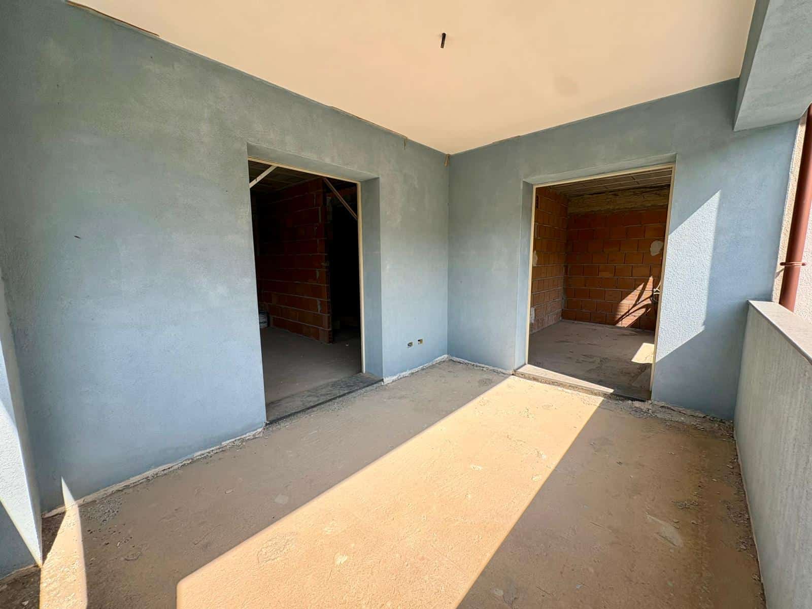 Interno di un appartamento in costruzione con pareti azzurre e porte aperte, pronto per finiture e arredi.